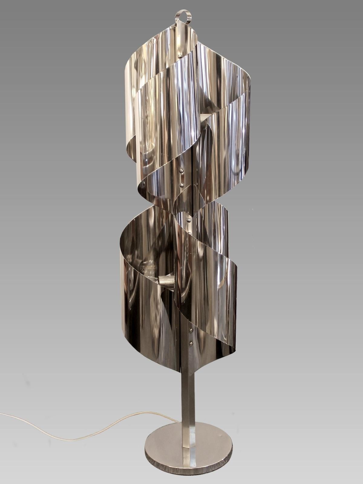 Floor lamp in the shape of a spiral, made of shiny stainless steel sheets formed and riveted on a central axis,
Italy, circa 1970.

Measure: Diameter of the base 11 in.