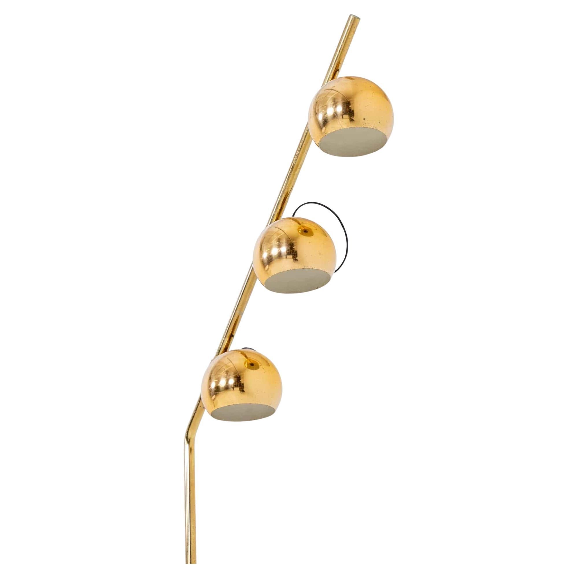 Golden floor lamp in polished brass with slender stem and three spherical lampshades.