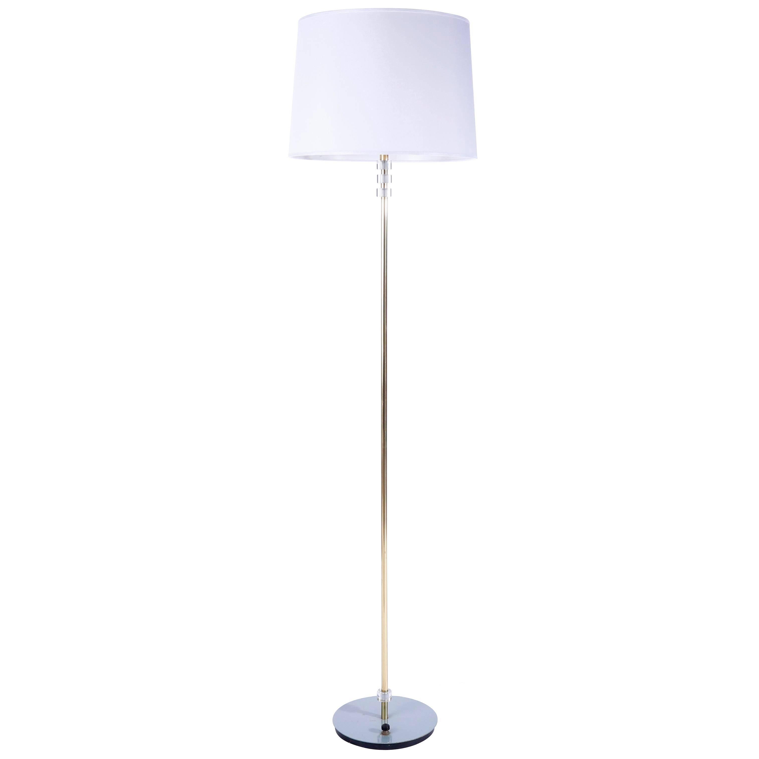 A brass floor lamp manufactured in midcentury, circa 1960 (late 1950s or early 1960s). 
The Stand is made of a brass rod and Lucite discs. The turquoise painted base has an integrated switch.
The light has two sockets for medium screw base LEDs or