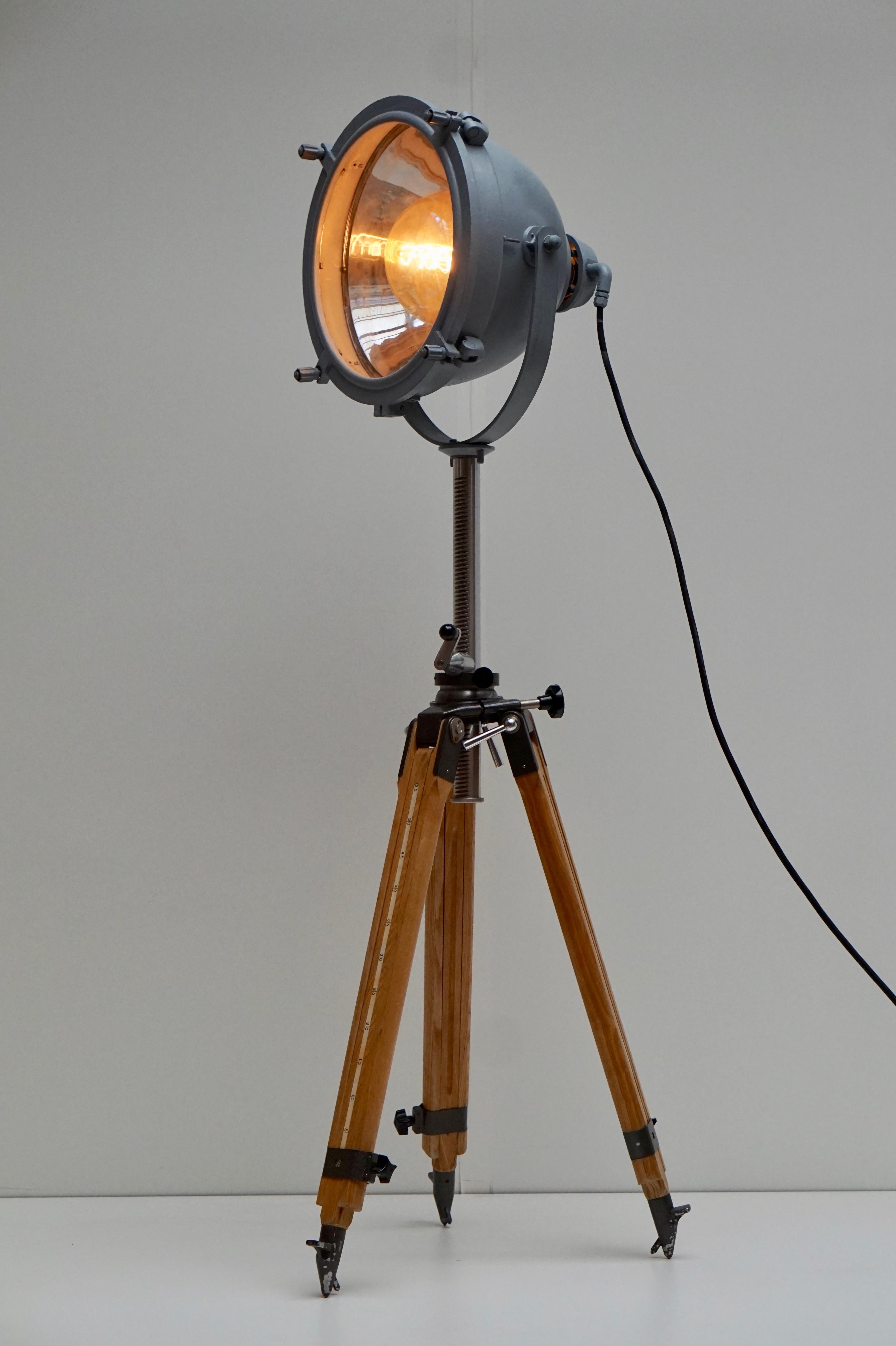 Un grand projecteur ou spot industriel vintage sur un trépied en bois, vers 1930-1950. En bon état vintage, recâblé et magnifiquement fini. 
Le lampadaire tripode est réglable et possède une ampoule E27.
Fabriqué par Francis Searchlights en