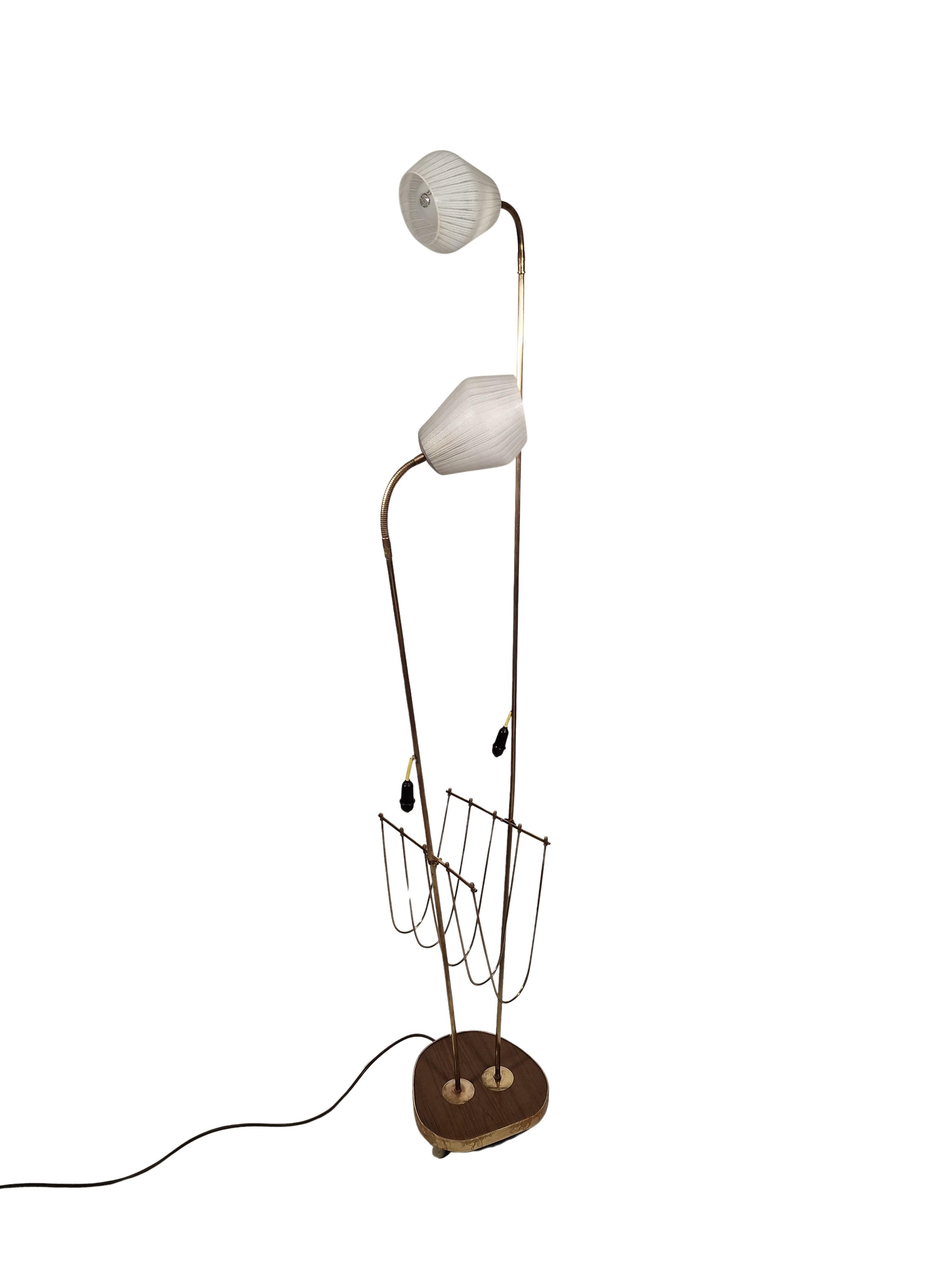 Ce magnifique lampadaire du milieu du siècle avec deux sources lumineuses réglables, offre également un porte-journaux, fabriqué dans les années 1950 en Autriche. 

Le design typique des années 50 montre une base asymétrique en bois, à partir de