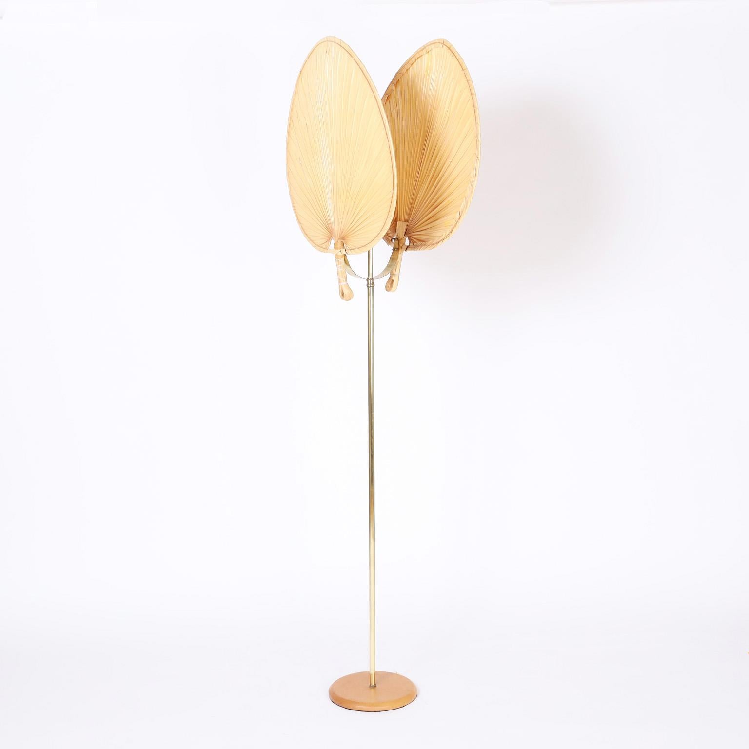 Organic modern floor lamp with an unusual use of materials, the fan shaped shades are crafted in palm fronds mounted on a brass pole over a round wood base.