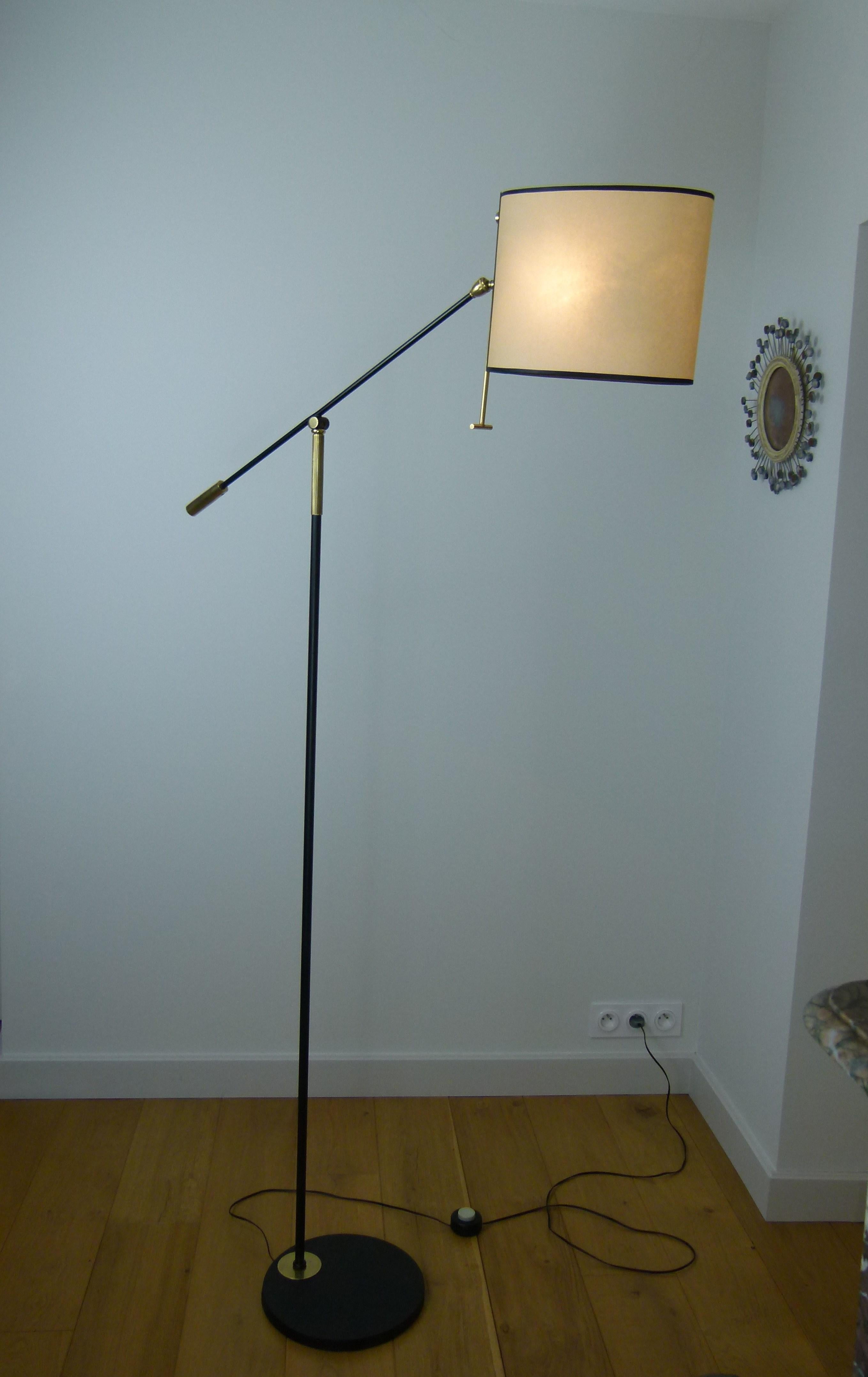 Floor lamp with pendulum in black lacquered metal and brass,
composed of a circular base in black lacquered cast iron,
on which is attached a lacquered metal arm, terminated by a hinged joint and adjustable by a brass handle.
On this ball is