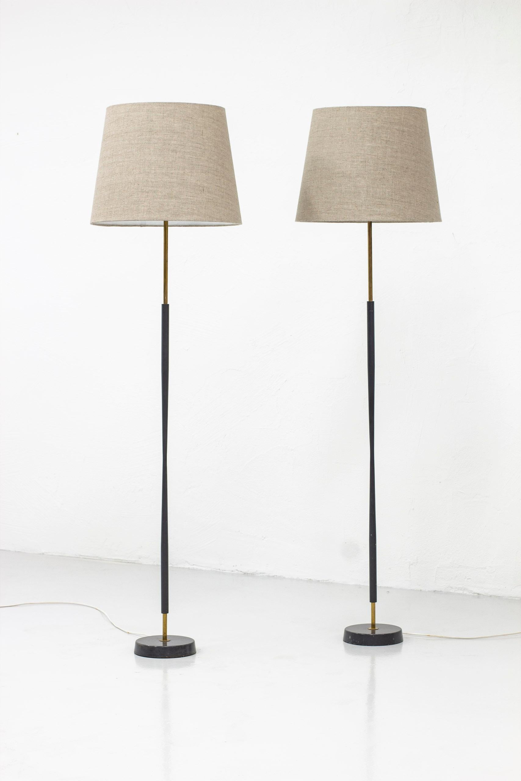 Floor lamps made by ASEA belysning in Sweden during the 1950s. Made from brass with a dark grey lacquer. New grey/natural linen lamp shades. Light switches on the lamp holders in working order. Good vintage condition with age related wear and