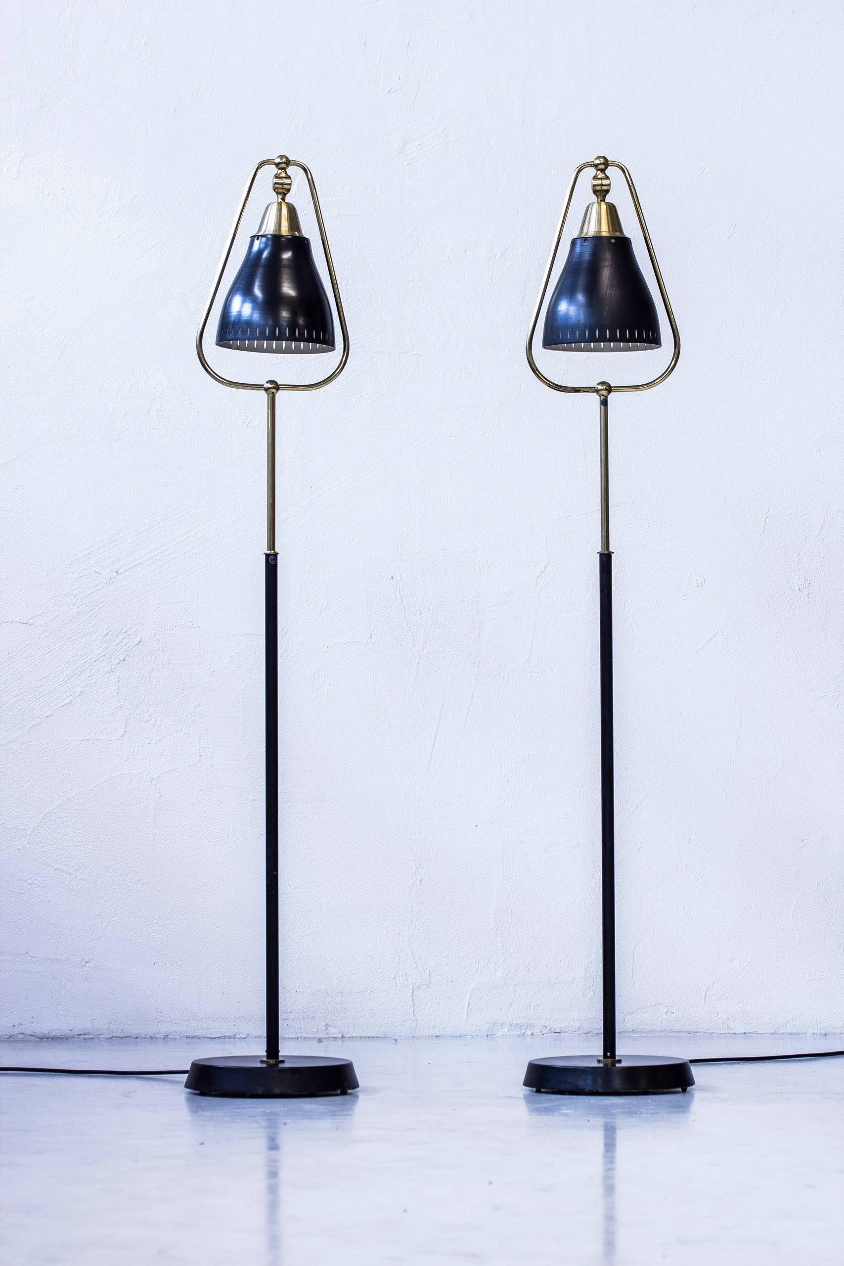 Pair of floor lamps produced in Sweden by Göteborgs Armaturhantverk. Made sometime during the 1950s. Bell shaped lampshade adjustable to work at both down light and reading light. Made from black lacquered metal and brass. New electric cables.