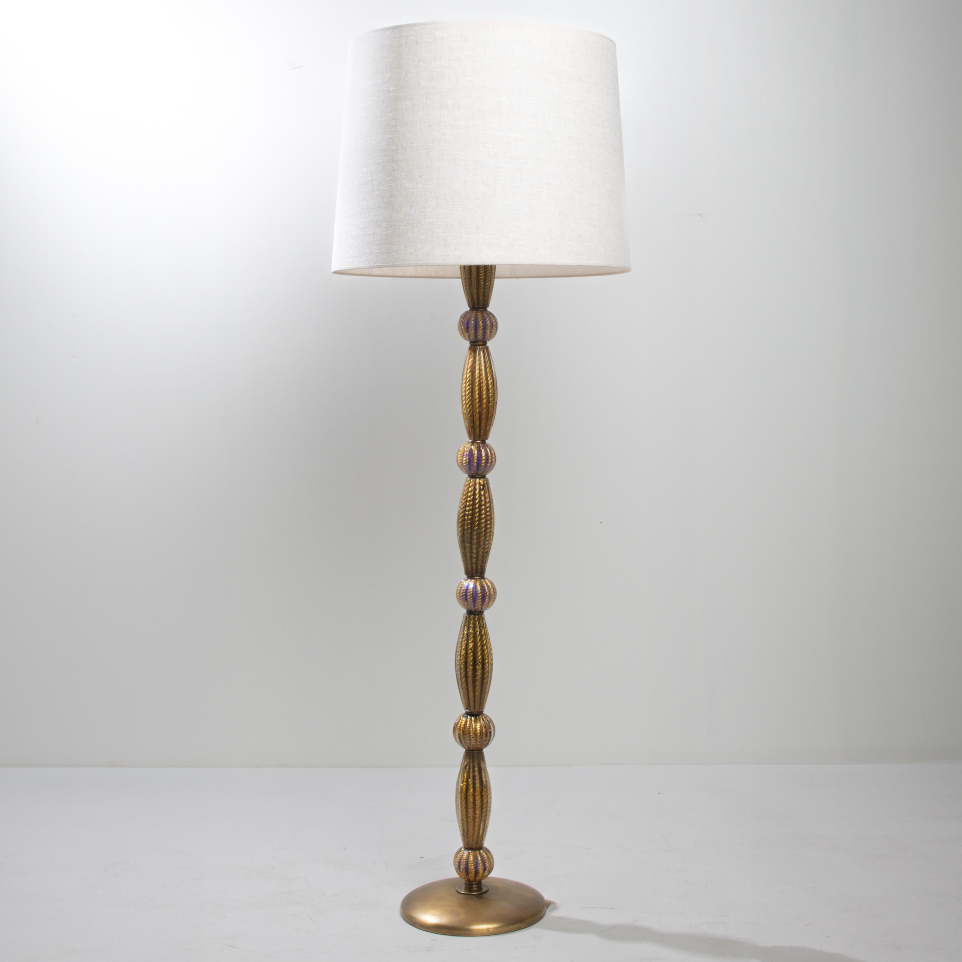 Spectacular floor lamp by Barovier & Toso.
The central steel barrel supports 10 mouth-blown Murano glass elements by Barovier & Toso. (5 oblong-shaped elements, 5 ball-shaped elements).
Blue glass decorated with gold “cords”. Technique called
