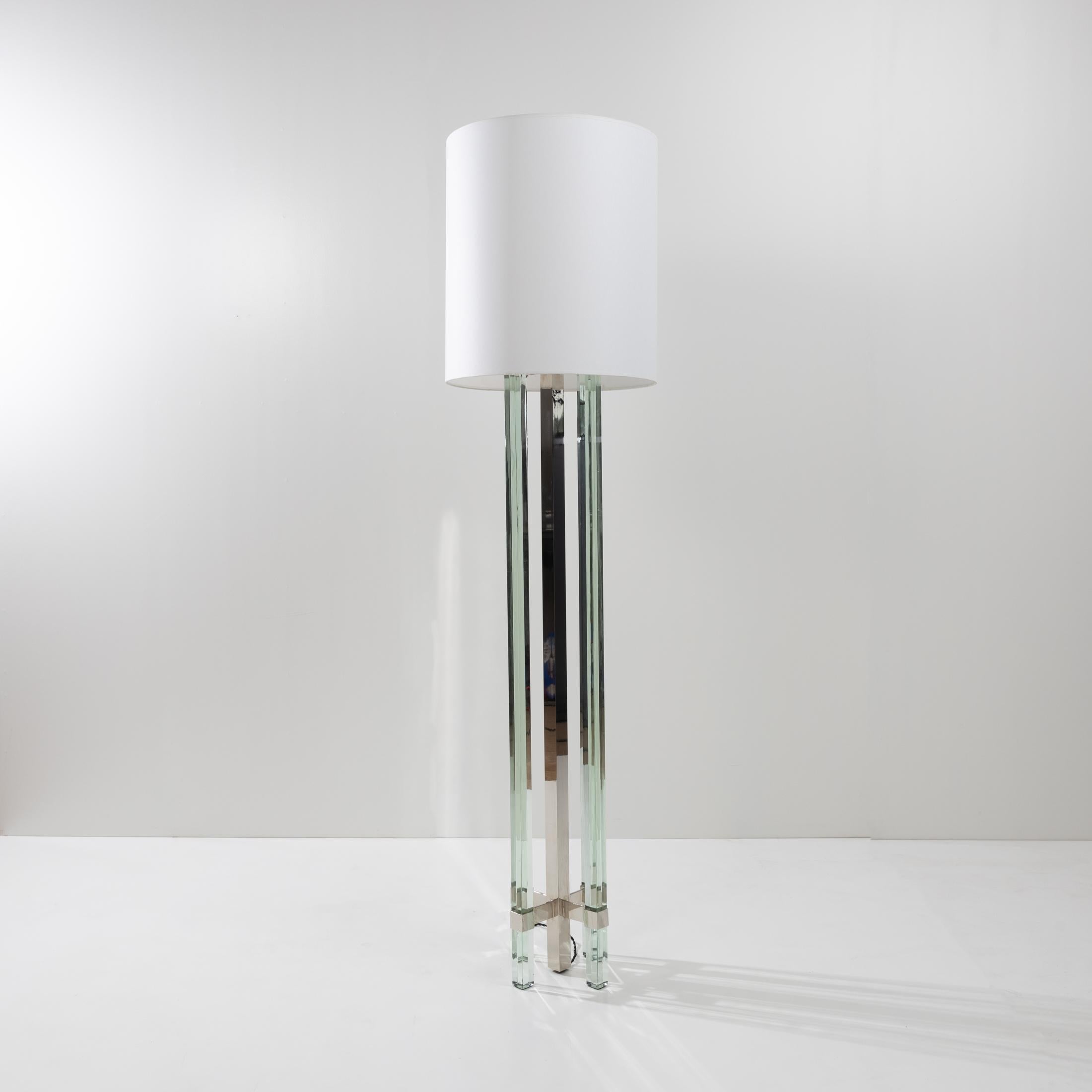 Floor lamp whose nickel-plated brass structure supports 4 large transparent / green colored glass legs fixed by two large cross-shaped spacers.
The floor lamp is equipped with a cylindrical shade (new and identical to the