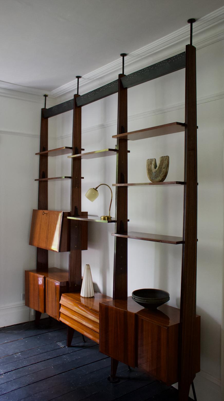 Modular floor to ceiling shelving system attributed to Dassi of Milan, Italy 1950s.

An impressive design with lots of interesting detail. The wood of this set looks to be rosewood, with a glossy varnish, and the metalwork is finished in black