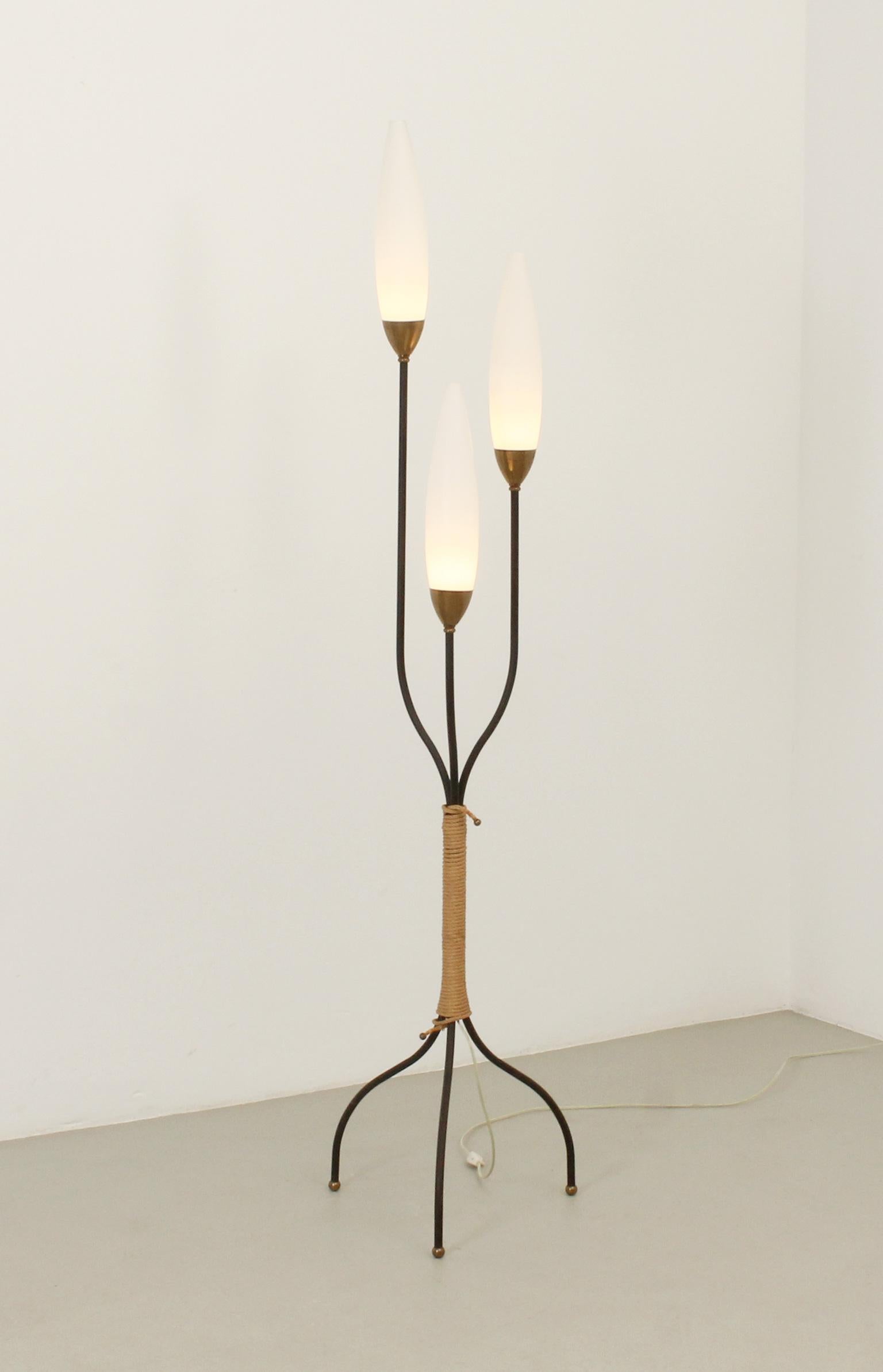 Floor tripod lamp with three lights by Maison Lunel, France, 1950s. Black lacquered metal with three opal glass diffusers and fittings in brass and cord.