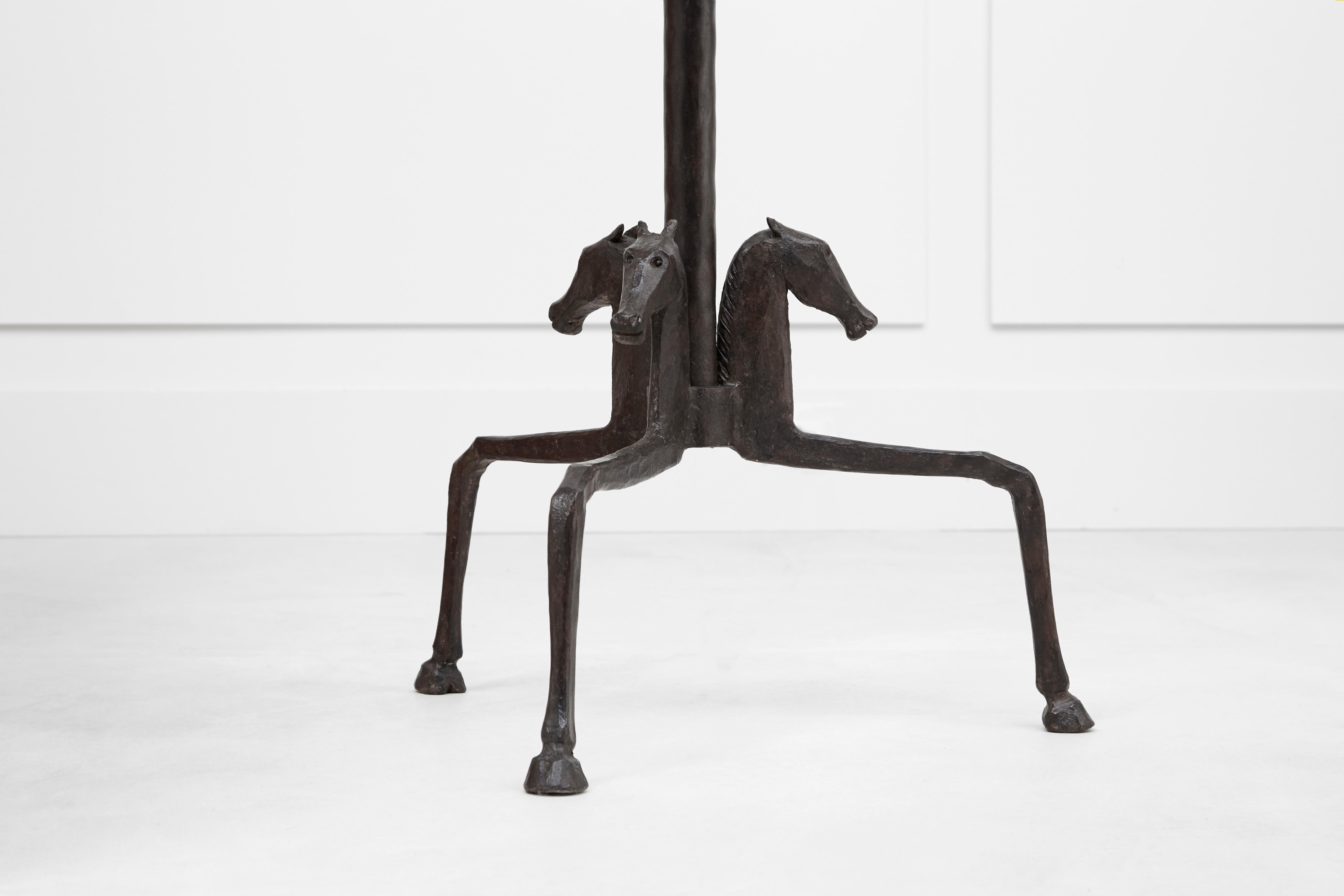 Brown patina wrought-iron floor lamp. The tubular shaft is decorated with a flat- ted disk on its middle, forged in only one piece ; the tripod base composed of three horses heads and legs, ending with hoof. Made by the famous metalworker Emil