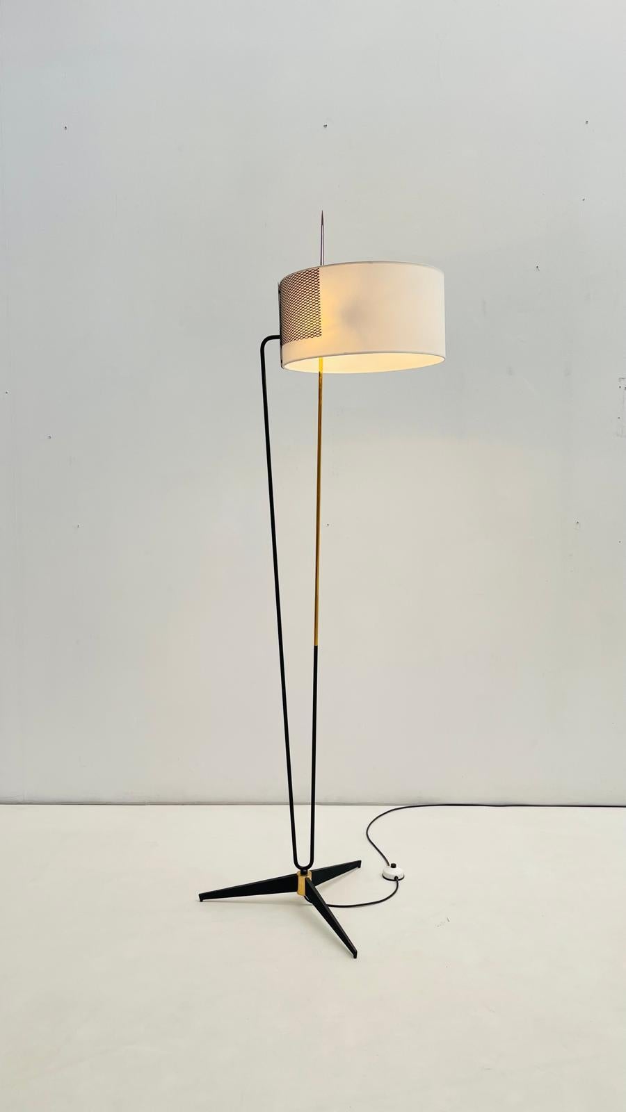 This floor lamp is a 1950s design by Maison Arlus, Paris. Its form is defined by a slender, graphic structure — a combination of black lacquered metal and a central brass rod that rises with quiet elegance. The bent support arm extends outward to