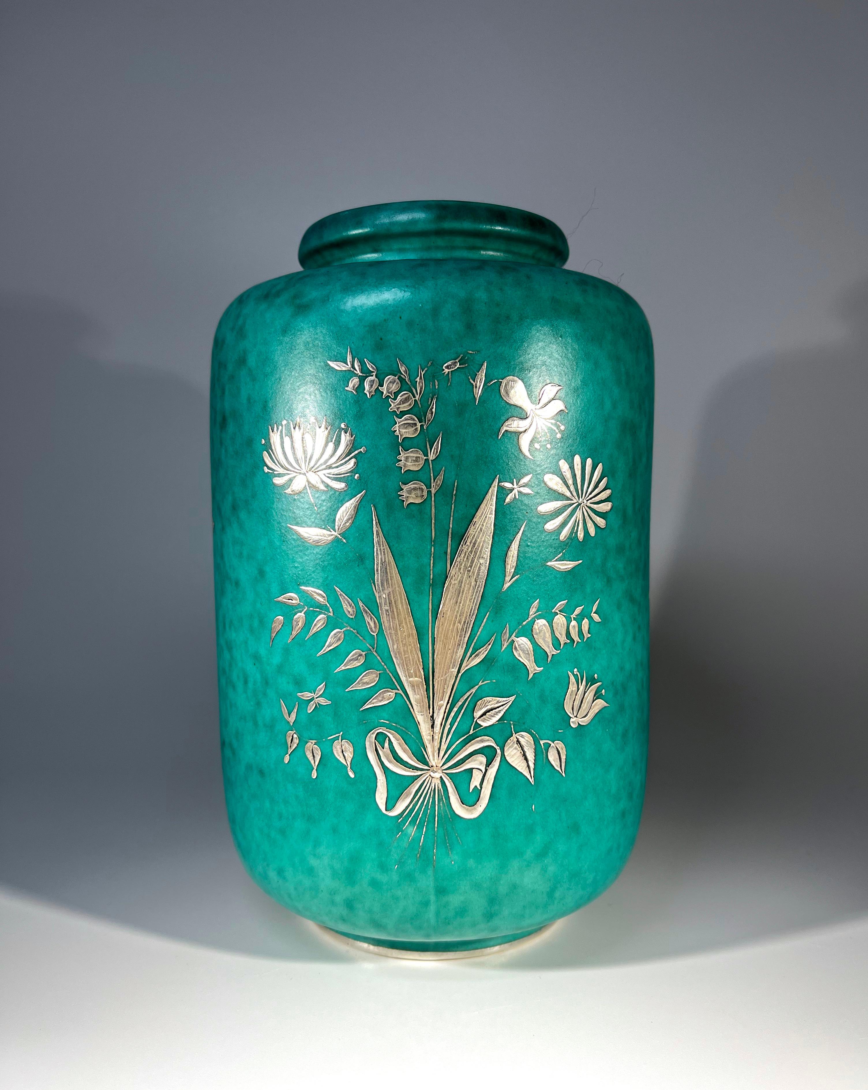 Zarte Zweige von Wildblumen und winzige Insekten schmücken dieses Stück aus der Argenta-Serie von Wilhelm Kage für Gustavsberg, Schweden
Wunderschöne Vase aus gesprenkeltem Steinzeug, verziert mit aufgelegter silberner Flora und Fauna
CIRCA 1949