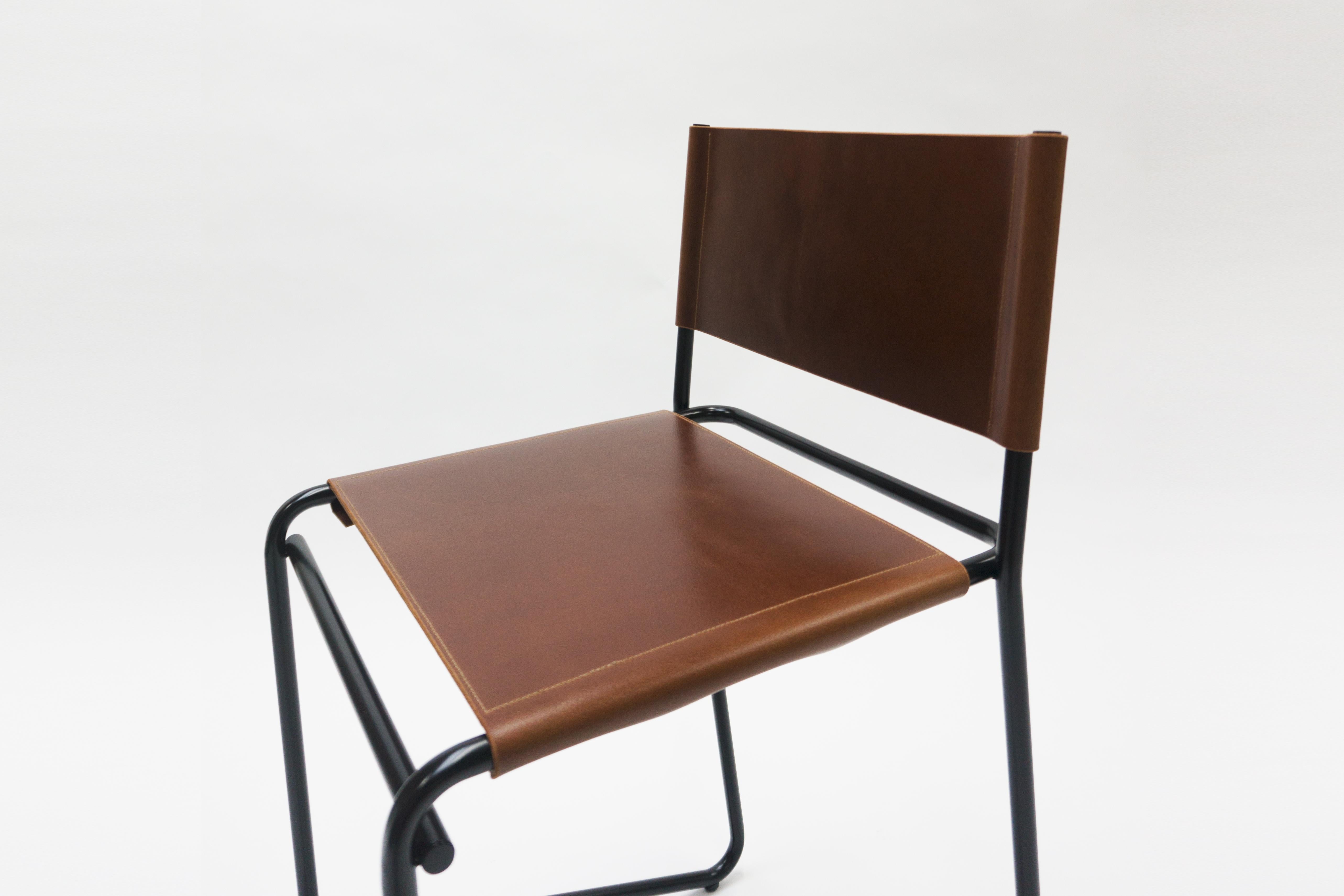 Le tabouret de bar Flora est composé de seulement trois pièces d'acier : une pièce arrière en forme de L qui touche le sol et remonte en angle pour créer un repose-pieds ; un siège rectiligne et un support avant ; et une barre transversale simple et