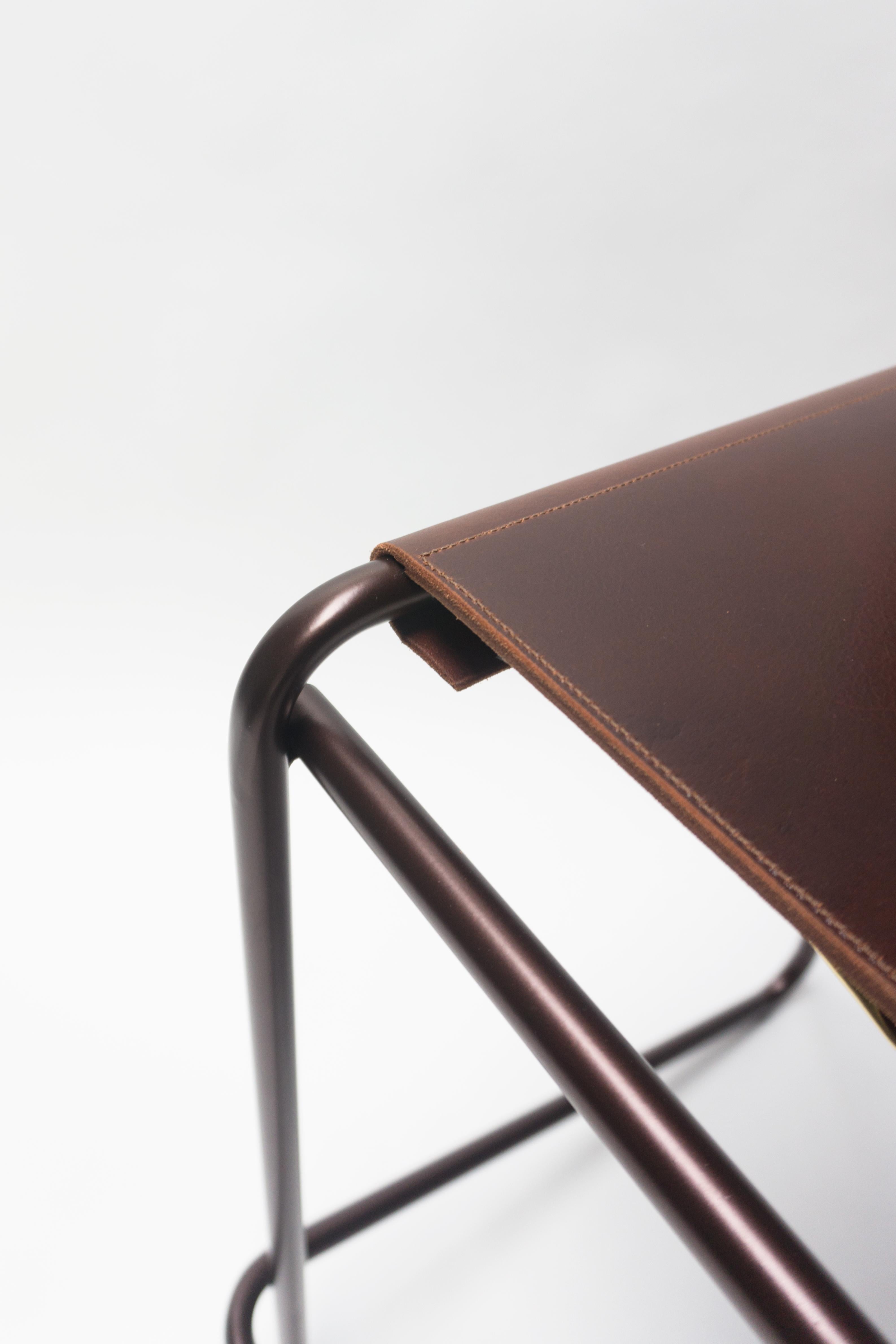 The Flora bar stool is composed of just three pieces of steel: an L-shaped back piece that touches the floor and rises up again at an angle to create a footrest, a rectilinear seat and front support, and a simple, stabilizing cross-bar across the