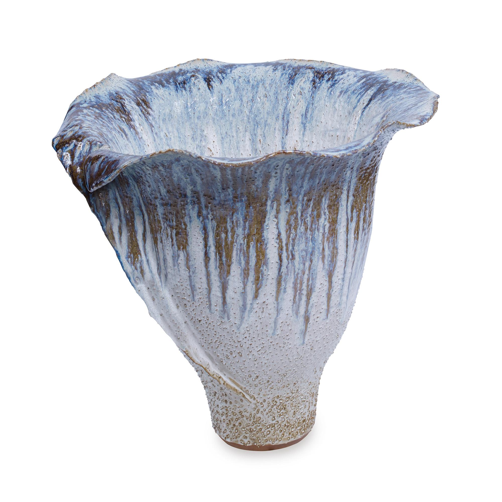 A flower-like shaped stoneware vase featuring a blue and neutral-toned reactive finish. Due to the handmade nature of this product, variation in size and color is to be expected.
 