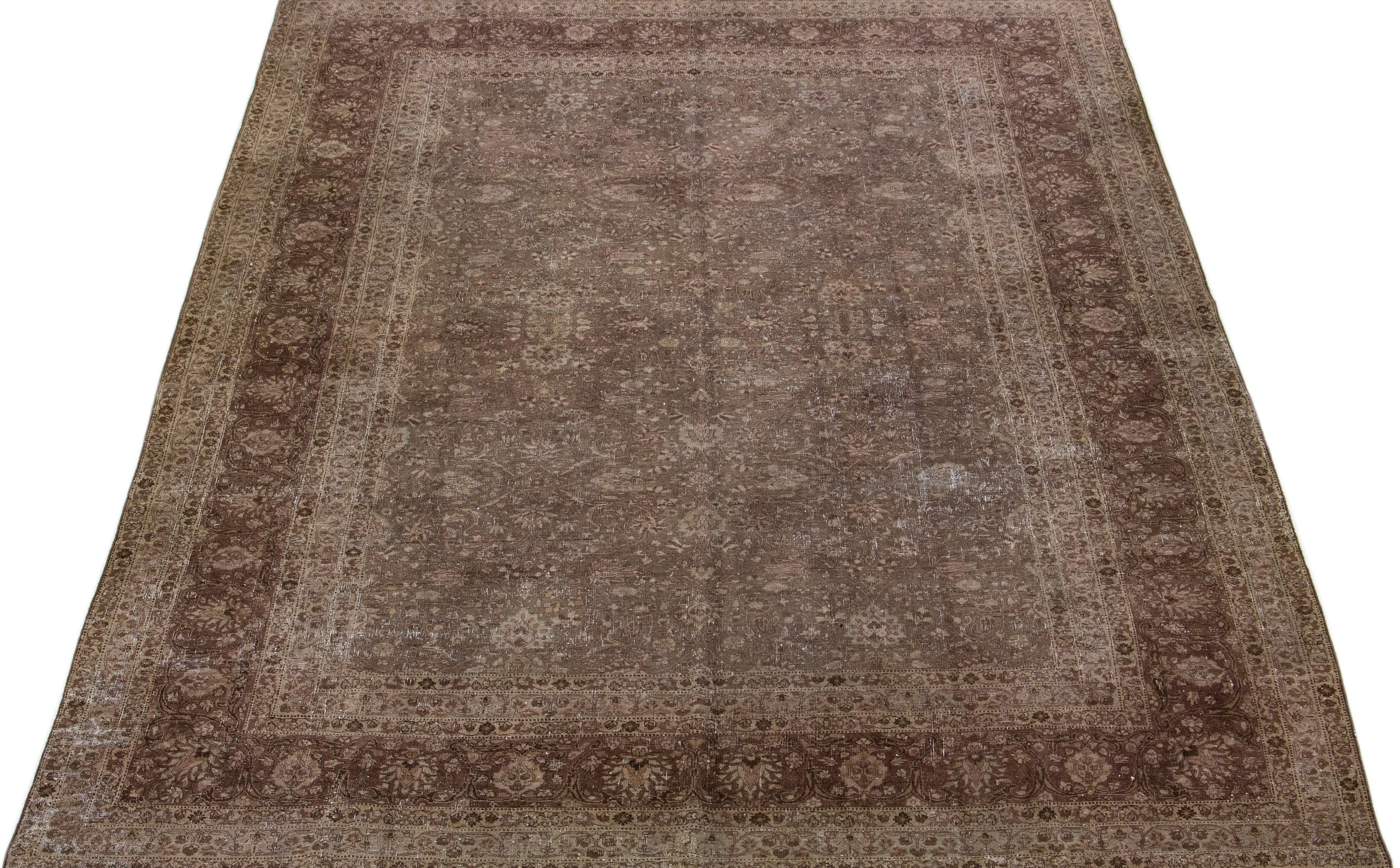 Beautiful antique Persian distressed Tabriz hand-knotted wool rug with a brown color field. This piece has a rusted frame with beige and gray accents in a gorgeous all-over floral design.

This rug measures: 10'6' x 14'10