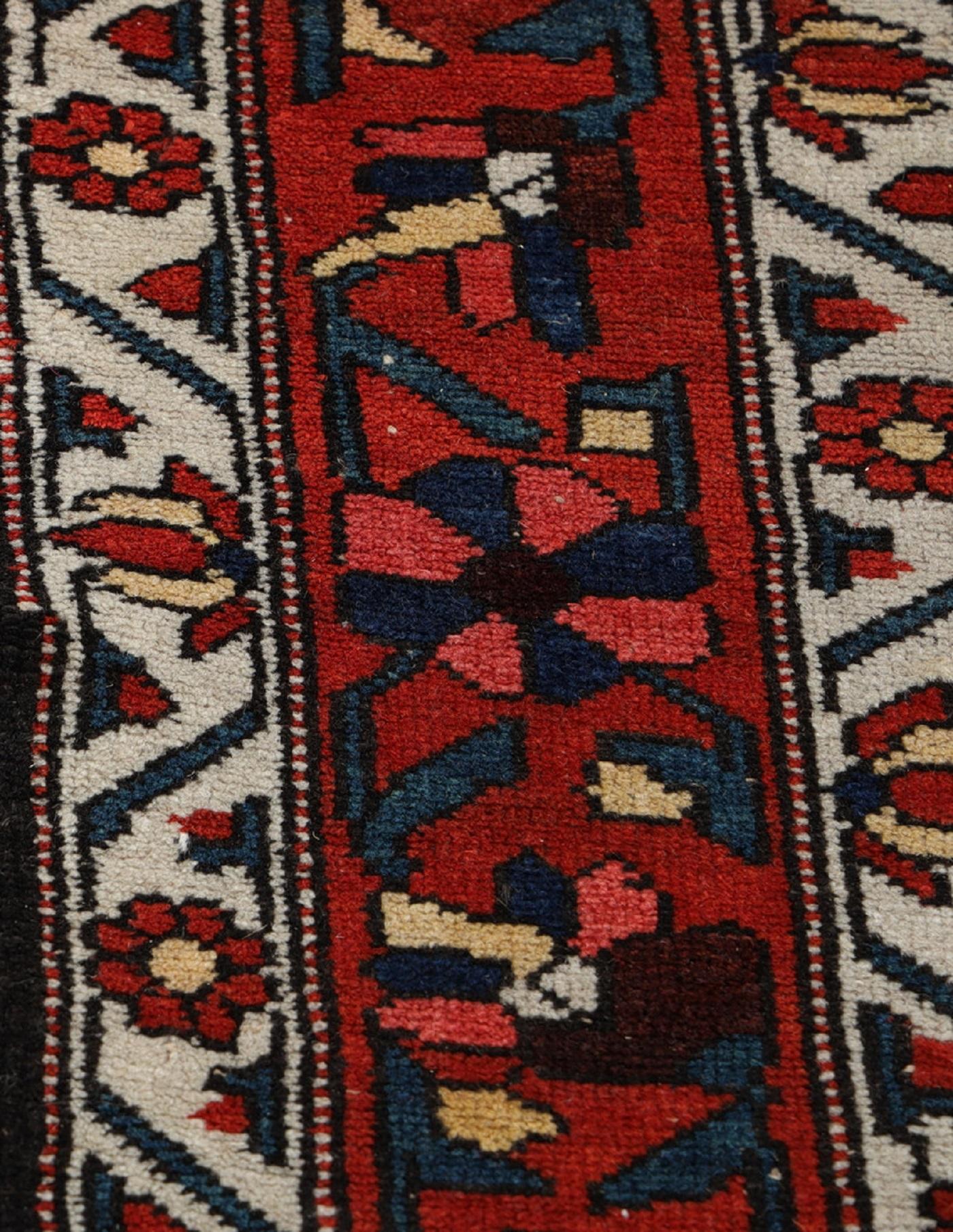 Ce tapis traditionnel tissé à la main a été fabriqué dans les années 1890. Il présente un médaillon central très détaillé, tissé sur un champ rouge profond, avec des accents de bleu ivoire et de rouge. Tissé à la main avec de la laine filée à la