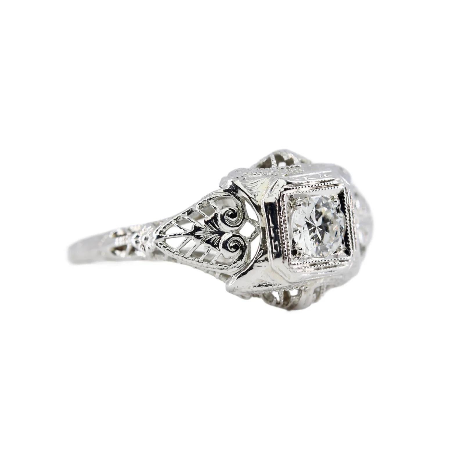 An original Art Deco period diamond filigree engagement ring. Featuring a beautiful floral motif design, this ring is centered by a 0.30 carat European cut diamond. Of G color and VS clarity the sparkling diamond sits framed by miligrain