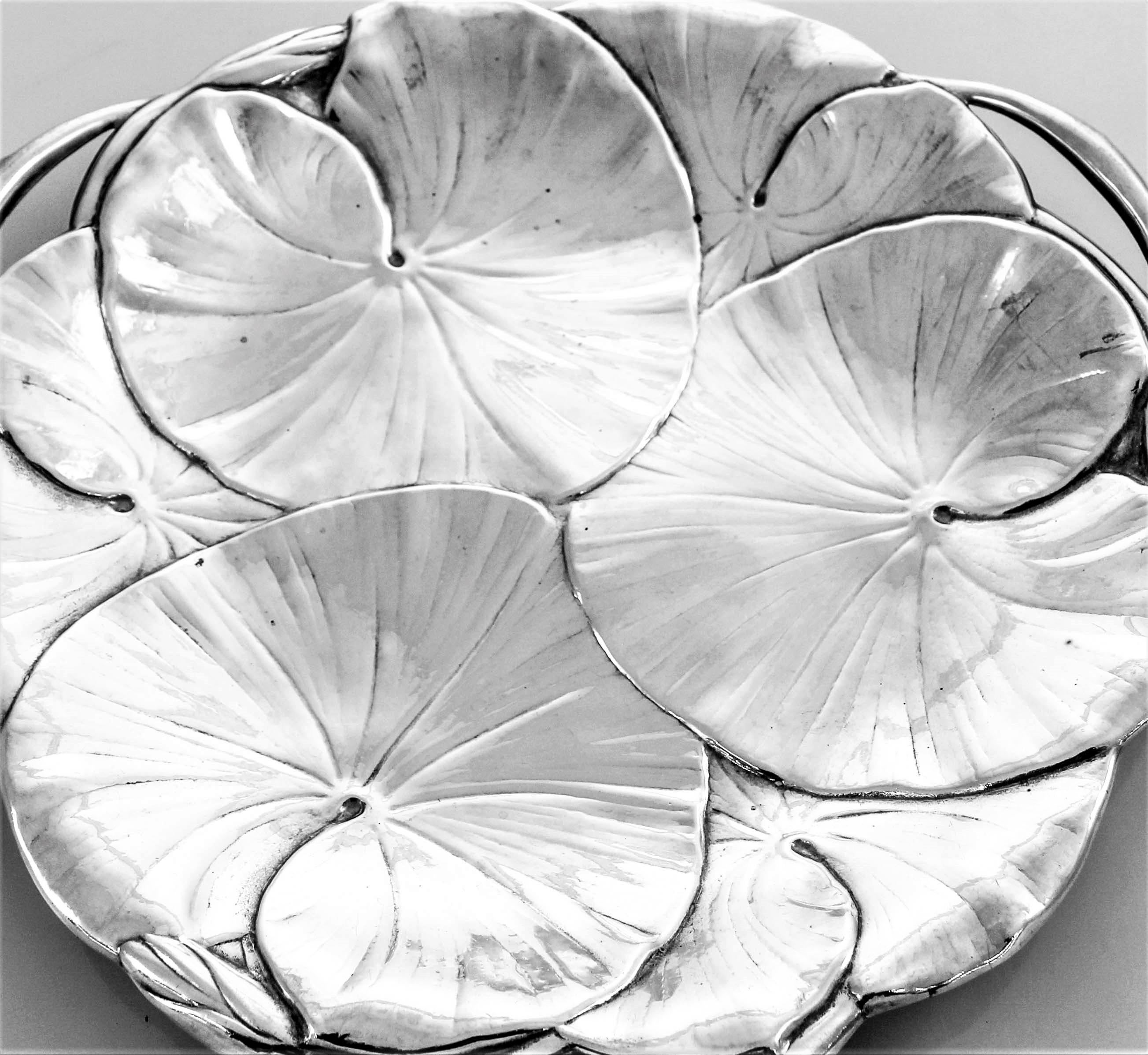 Three large lily pads make up the top of this sterling Art Nouveau dish. The Art Nouveau style was inspired by natural forms and structures, particularly the curved lines of plants and flowers. It has three cutouts along the edge as handles. Handles