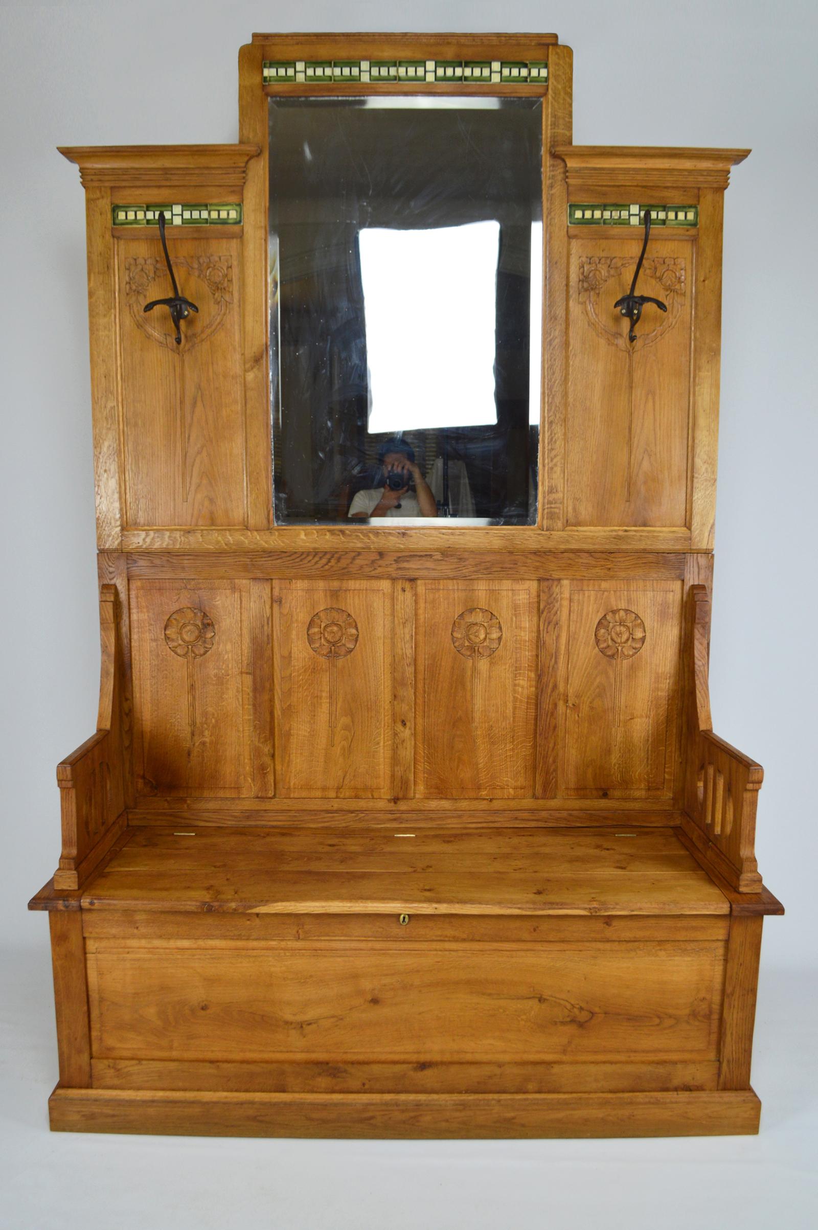 Amazing huge hall chest bench with coat racks in carved oak wood.
Carved on a floral theme.
Art Nouveau / Liberty, Italy, circa 1900.

In 2 parts:
-Upper part: huge beveled mirror, 2 cast iron hooks, carved flowers (roses), ceramic