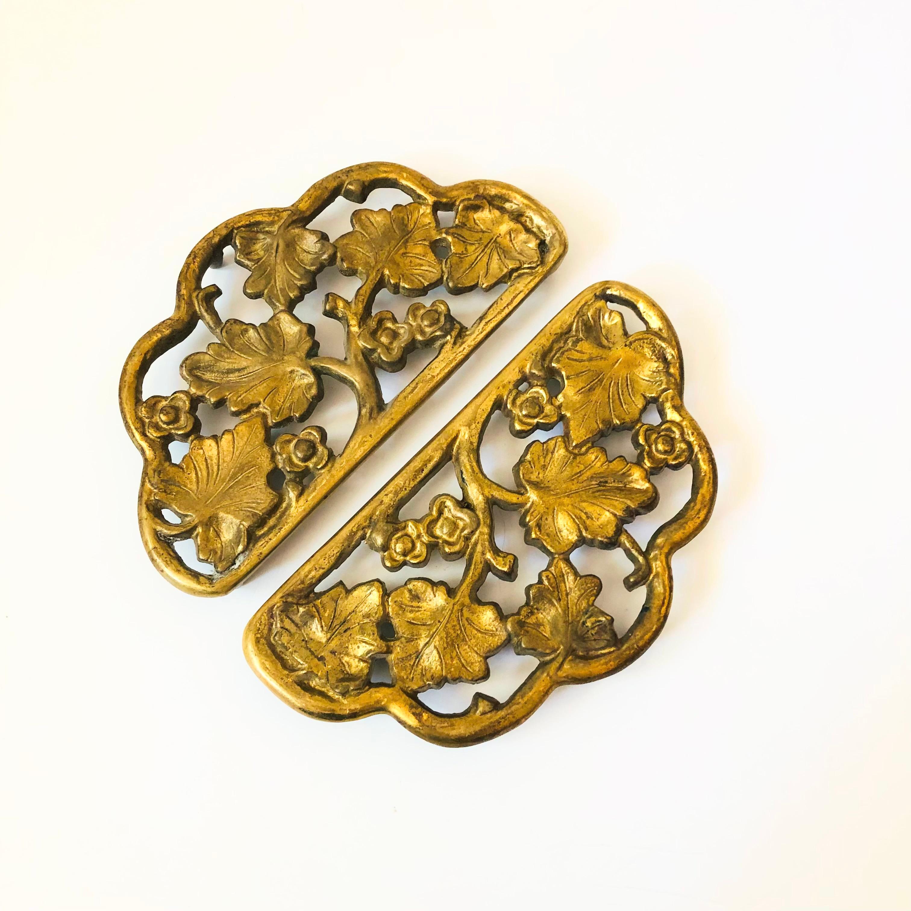 Un par de salvamanteles vintage de latón. Preciosos detalles florales en toda la pieza, cada uno de ellos en forma semicircular.

