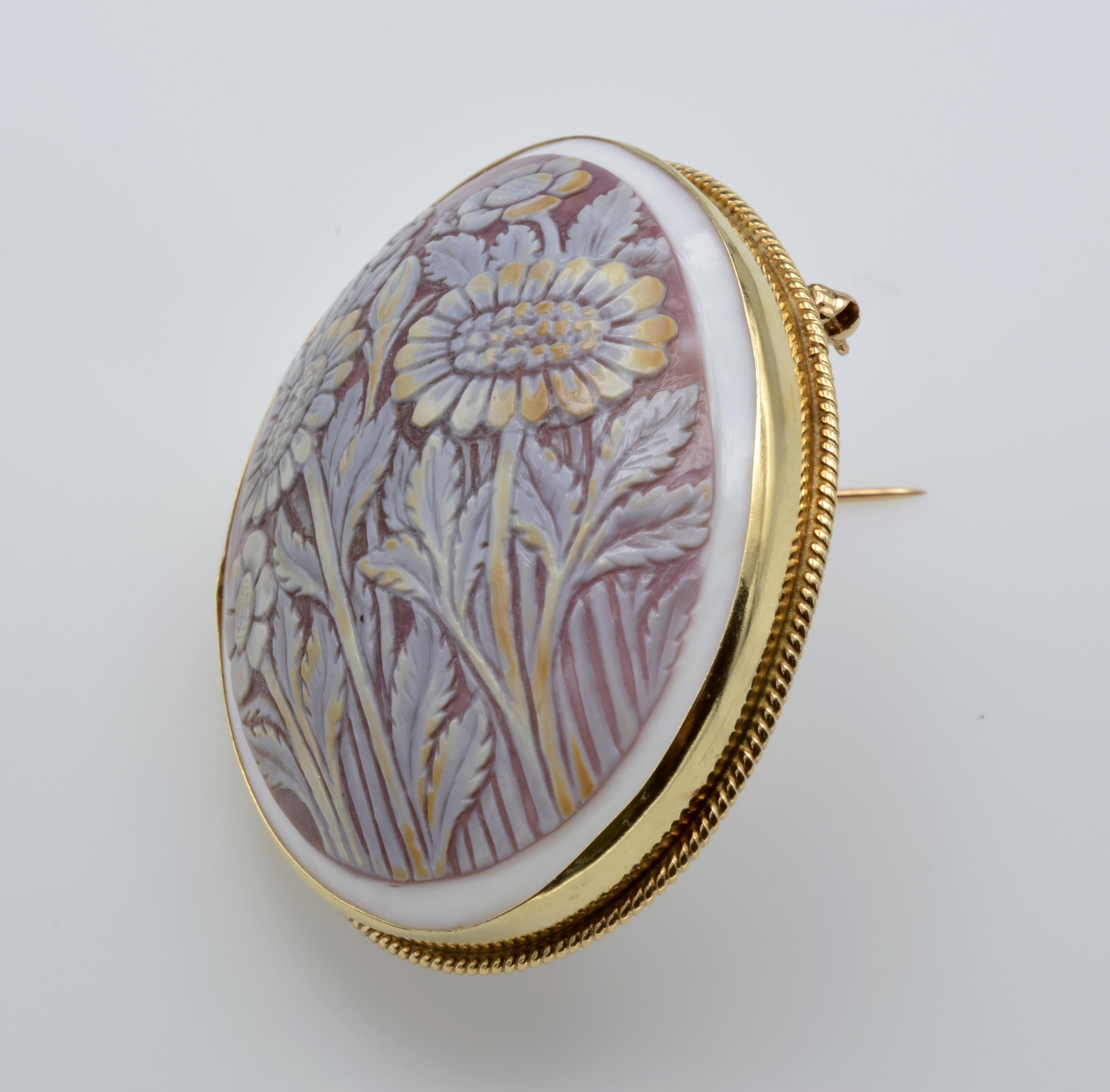 This unique cameo pin/ pendant is a floral motif that is very detailed and well proportioned. The 14k gold bezel has an intricate rope detail that beautifully frames this modern cameo. There is a hidden loop at the top for adding your favorite