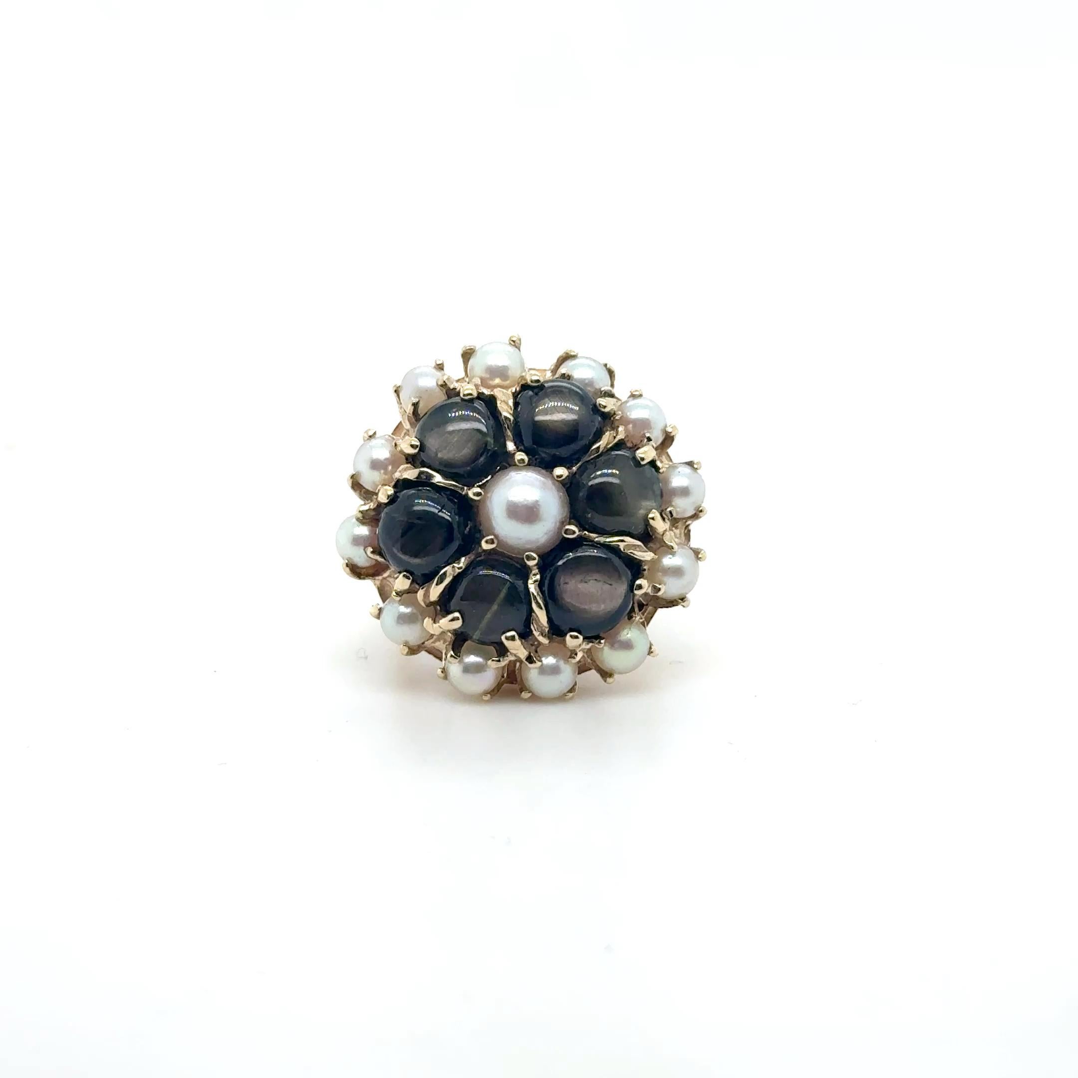 Questo splendido anello floreale in oro giallo 14K è un pezzo unico e lussuoso, caratterizzato da una straordinaria combinazione di sei zaffiri neri a stella per un totale di circa 4,5 carati. Ogni zaffiro presenta un asterismo naturale simile a una