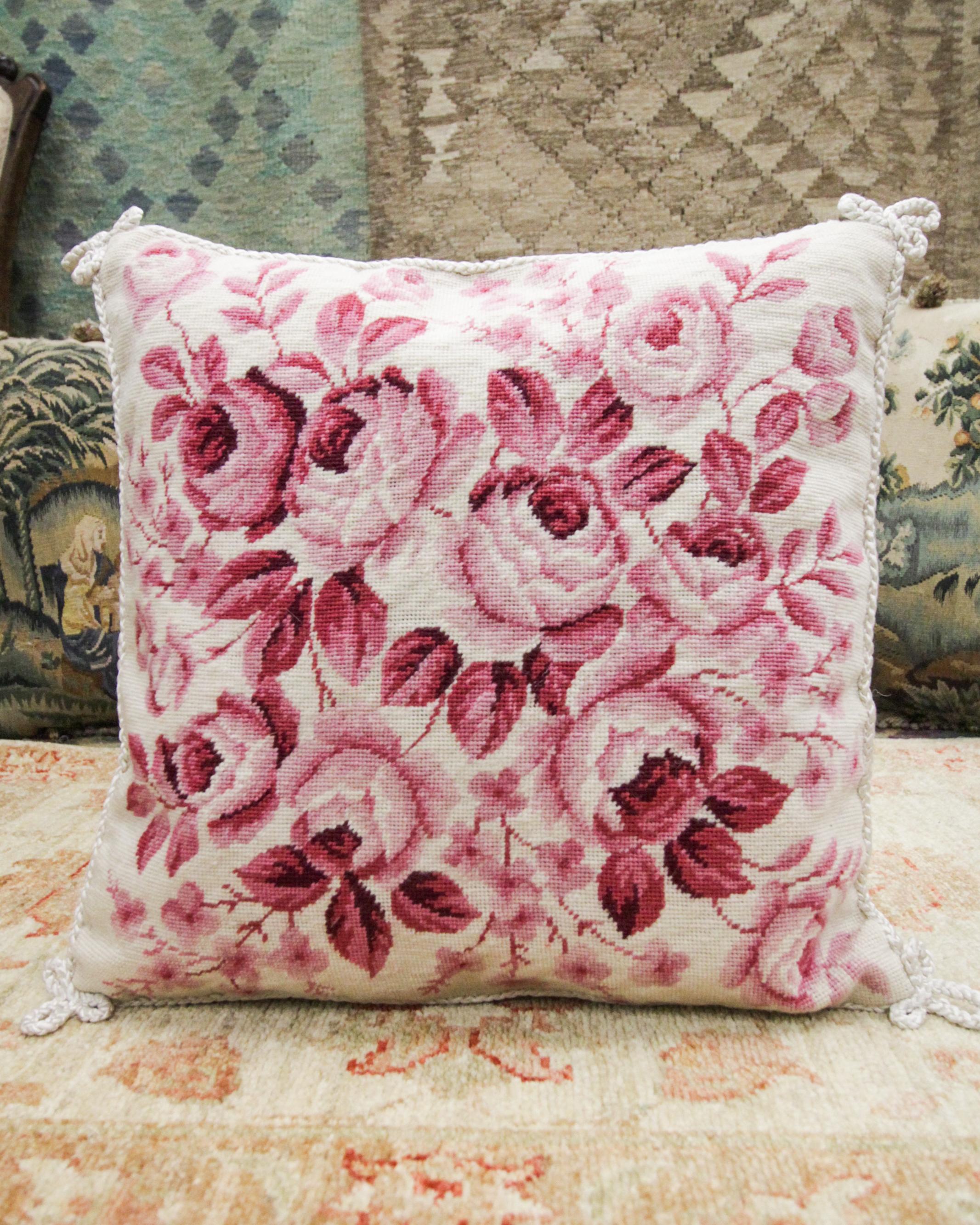 This floral needlepoint cushion cover is an excellent example of vintage cushion covers woven in the 1990s. The floral pattern has been woven in rich pink tones on a subtle cream background, detailed with a rope edge and corner design. The colour