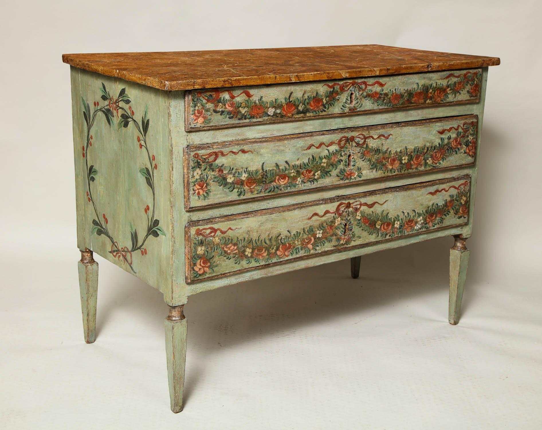 Very fine 18th century Italian, probably Venetian three-drawer commode, the top faux painted to simulate Sienna marble, over three graduated drawers festooned with floral and ribbon swags, standing on square tapered legs with ring turned collars,