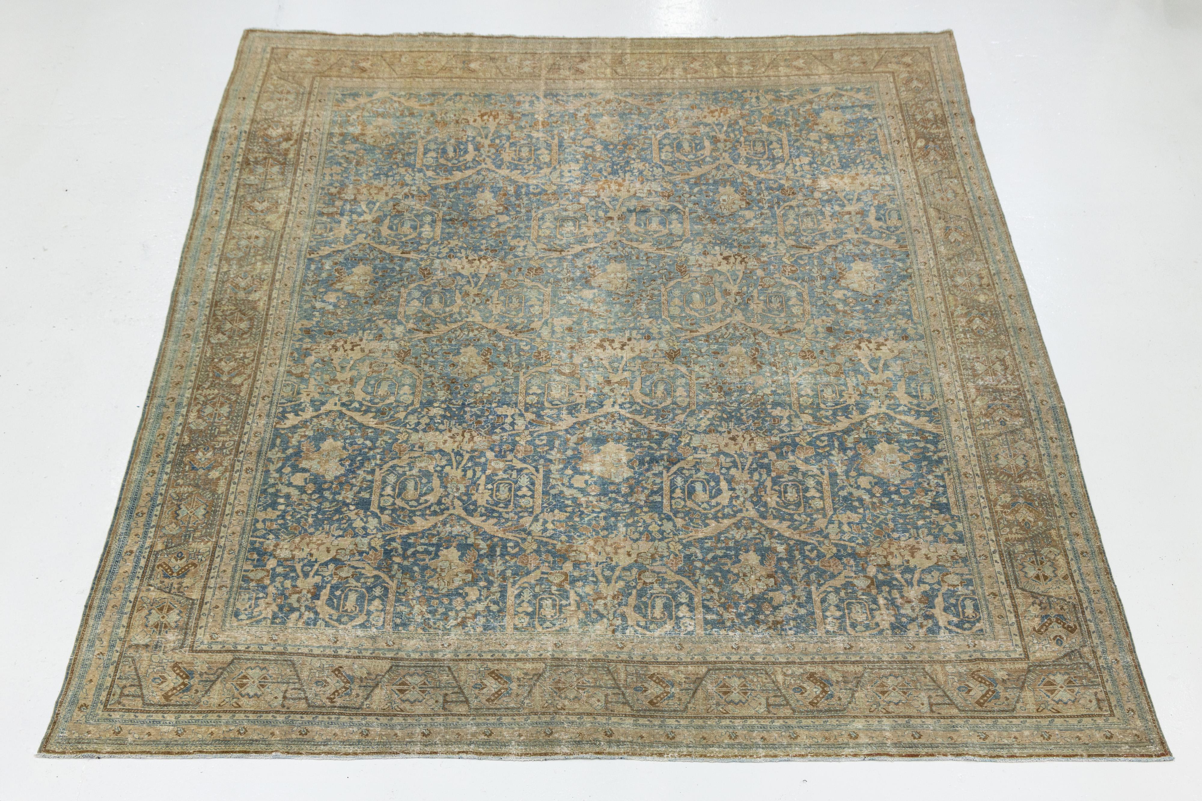 Dieser Mahal-Teppich aus Wolle wurde um 1900 in Persien handgeknüpft und zeigt ein anmutiges indigoblaues Feld mit beige- und walnussfarbenen Blumenmotiven. Das gitterartige Weinwerk und die geometrischen Bordüren spiegeln klassische persische Kunst