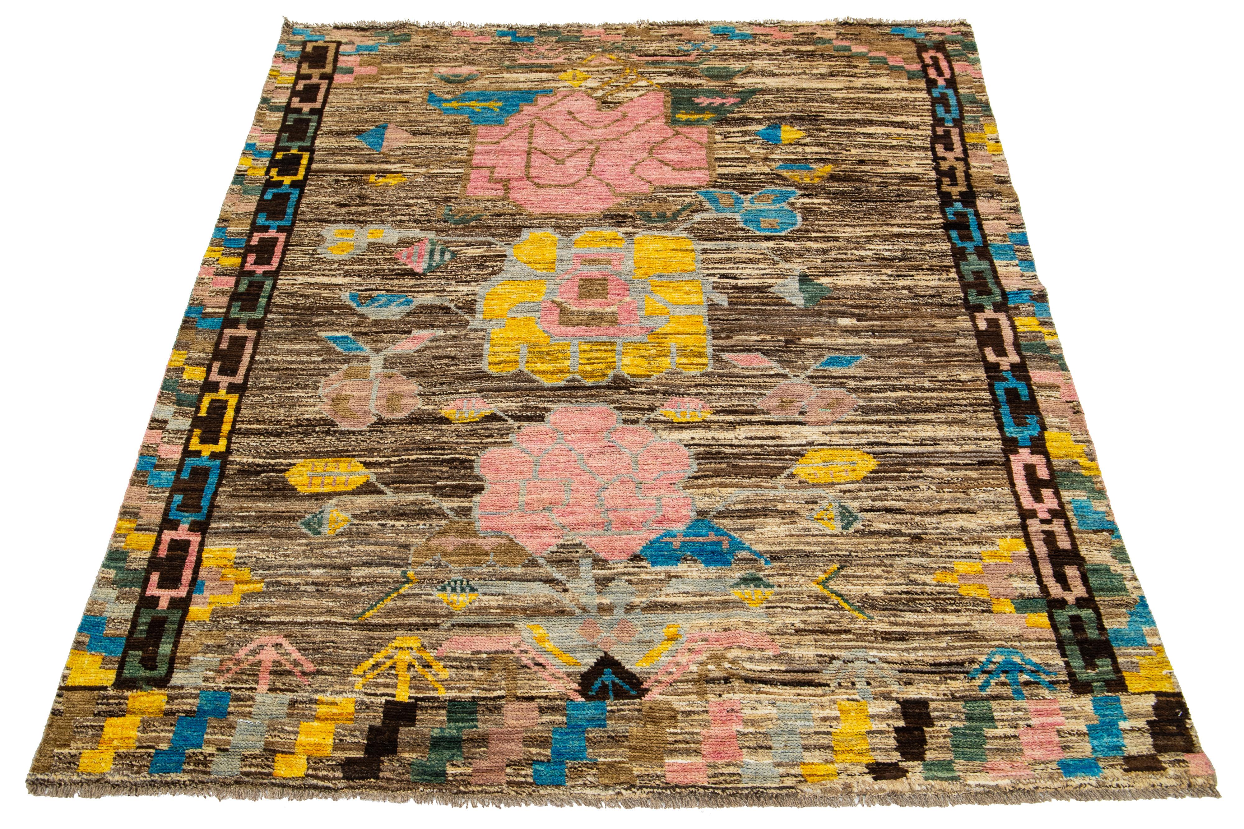 This contemporary Moroccan-style wool rug features a captivating brown field with peach, blue, and yellow flowers crafted in an all-over pattern.

This rug measures 5'10
