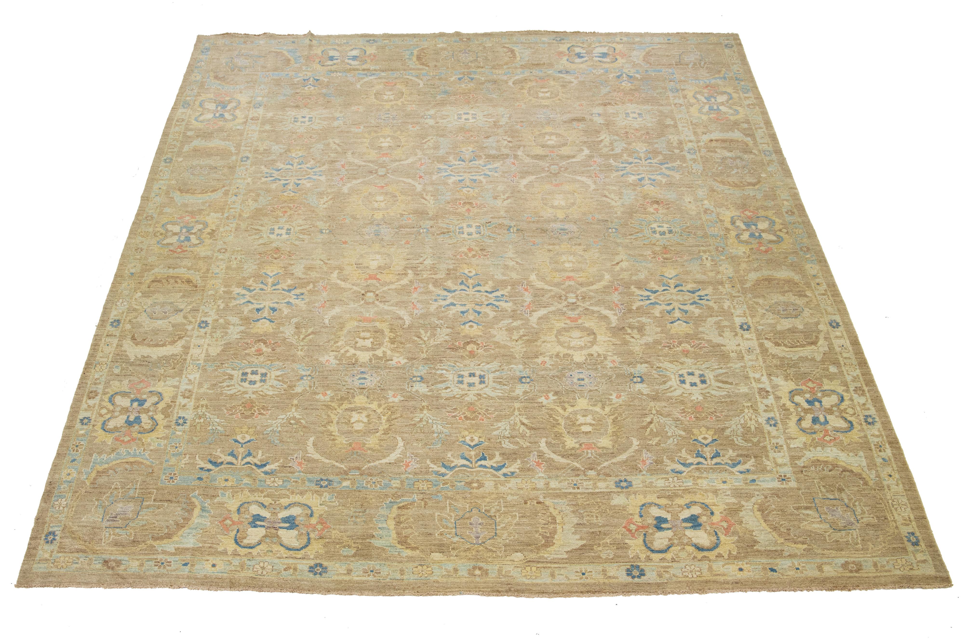 Dieser übergroße, handgeknüpfte Wollteppich zeigt ein hellbraunes Feld mit einem blauen, beigen und orangefarbenen Blumenmuster.

Dieser Teppich misst 12'3'' x 15'8''.