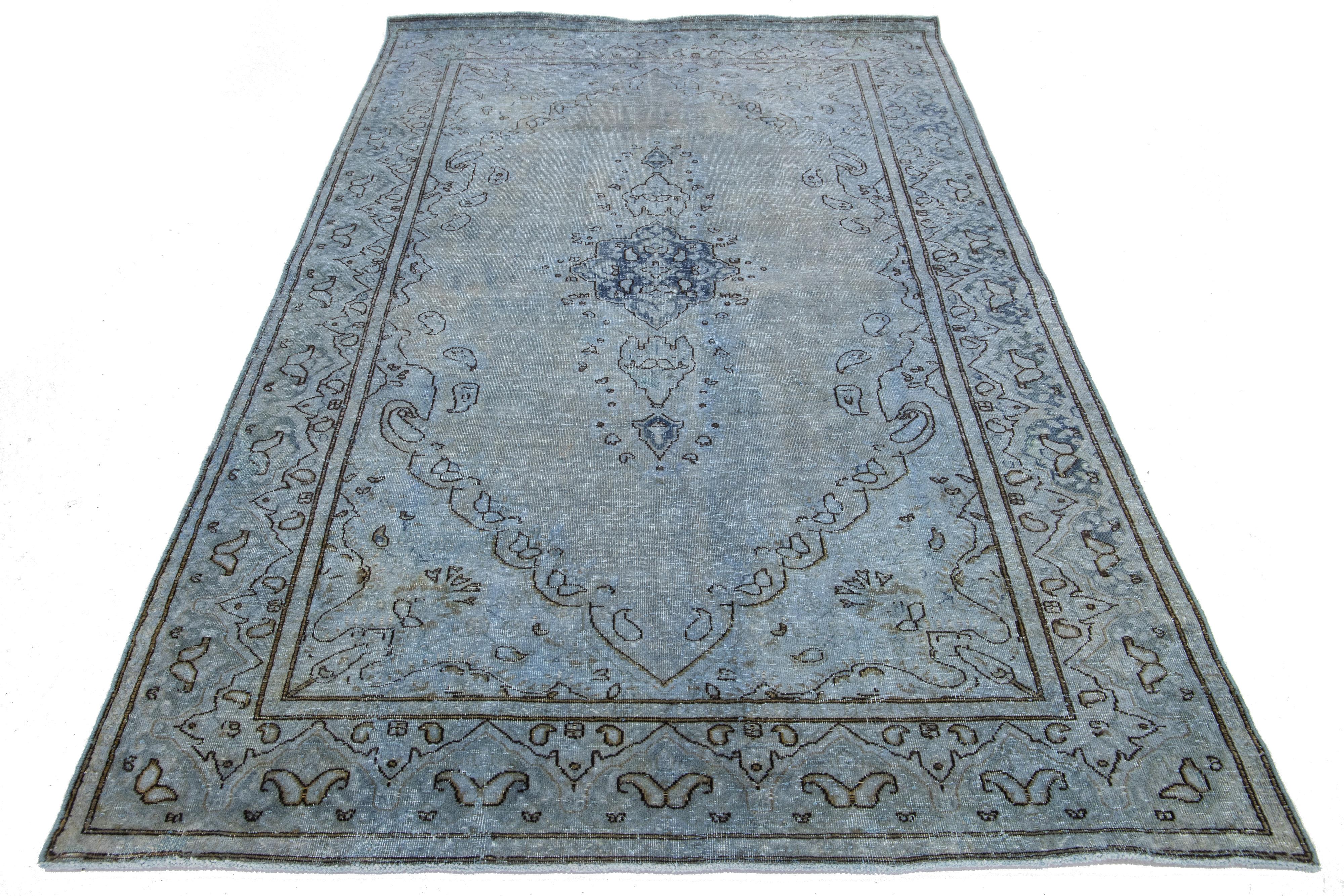 Dieser Vintage-Teppich aus gefärbter persischer Wolle besticht durch ein blaues und graues Farbfeld mit charmanten schwarzen Blumenakzenten.

Dieser Teppich misst 4'8