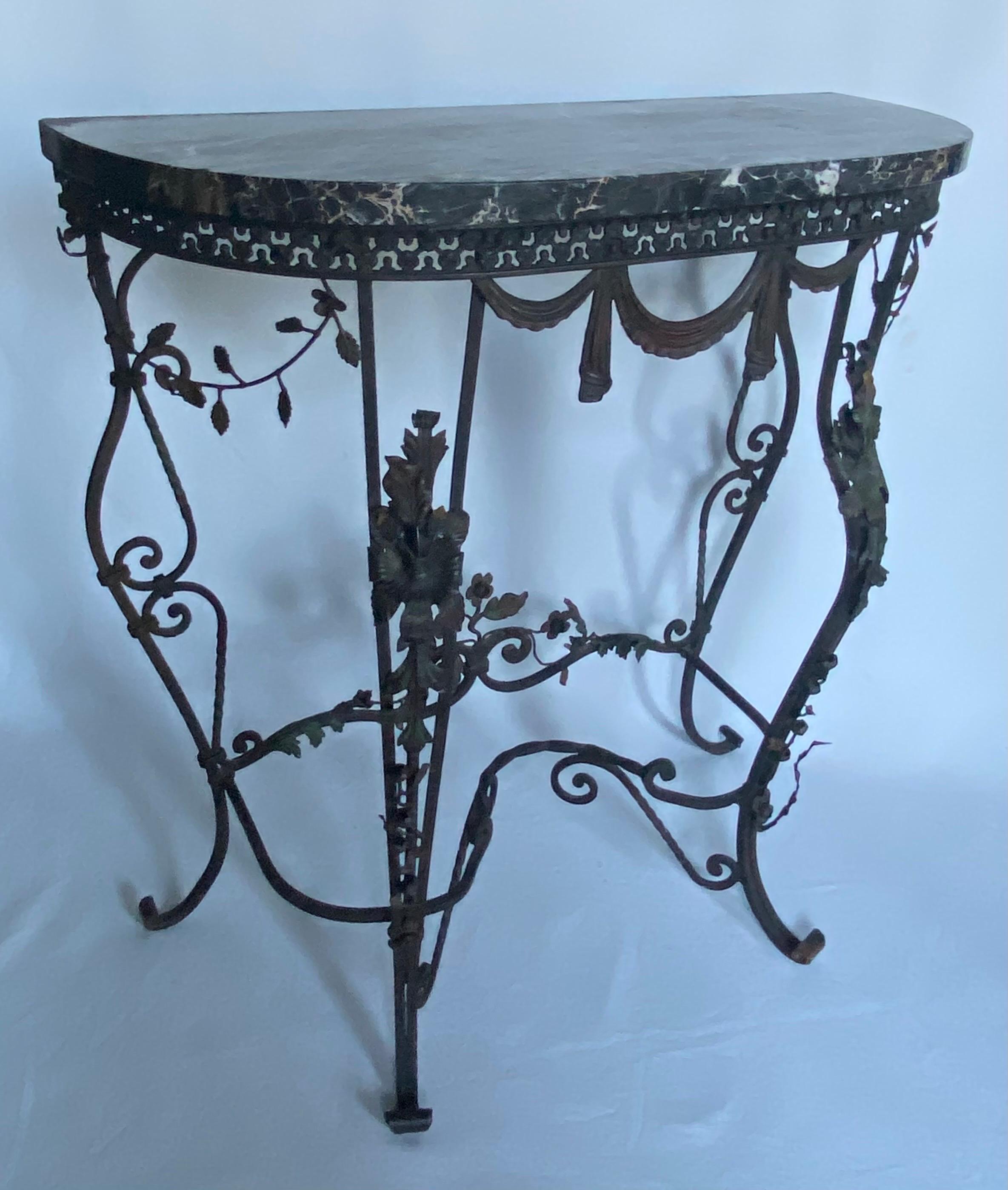 Jolie table console en fer forgé français avec un plateau en marbre noir magnifiquement veiné. Cette table en forme de demi-lune très décorée présente des motifs floraux botaniques et des guirlandes drapées. Une qualité de fabrication et un style