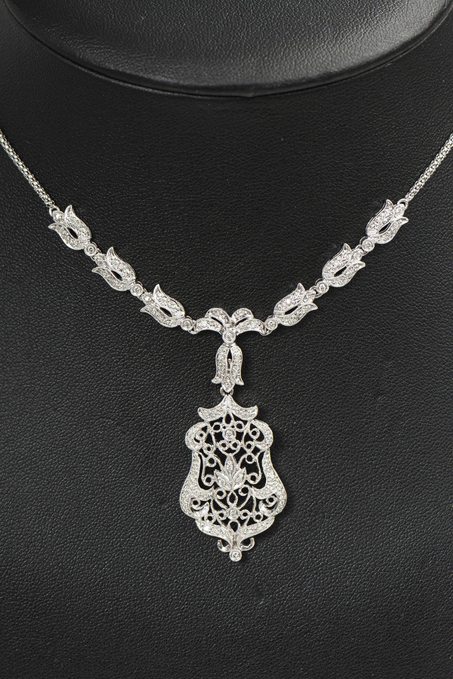 Delicate diamond 14k white gold necklace featuring a floral and scroll filagree design drop pendant necklace.  The back part of the chain is a weave pattern and the front near the pendant has six diamond tulip like flowers with a centralized diamond