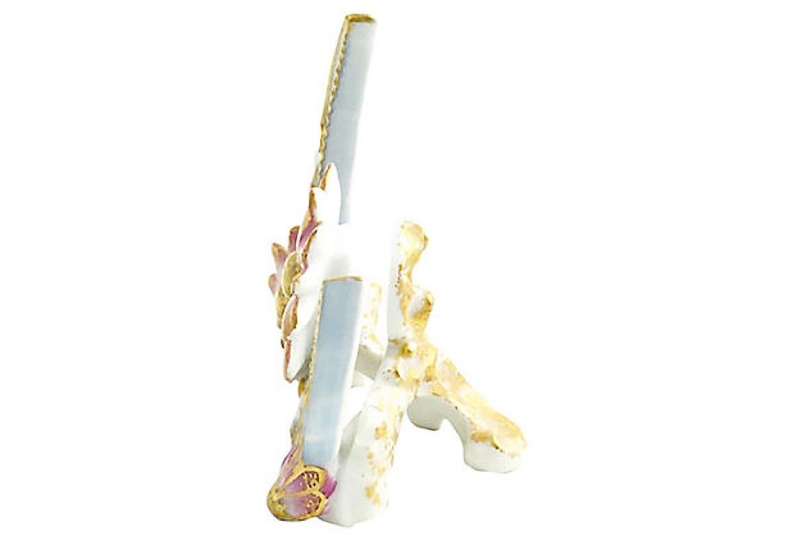 Porcelain menu holder featuring a pale blue crescent moon with gold beading on inner edge. Accented with three pink and gold flowers. Space between moon and gilt white easel accommodates a menu. Age wear.