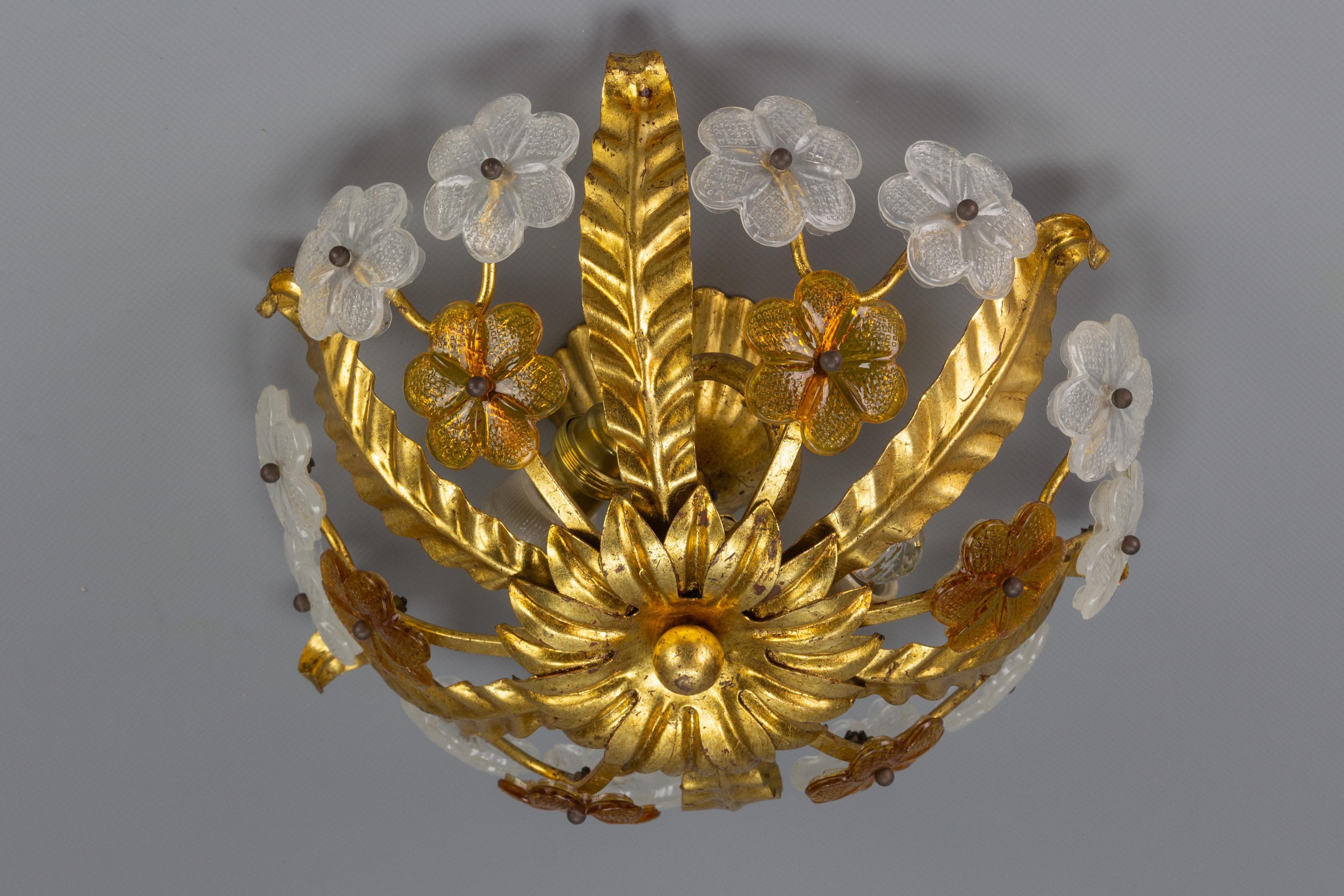Adorable and compact Hollywood Regency-style ceiling light fixture. This vintage flush mount features a gilt tole leaf-shaped frame that is adorned with white and brown glass flowers. It looks beautiful lit as well as unlit. Germany, 1960s.
Two