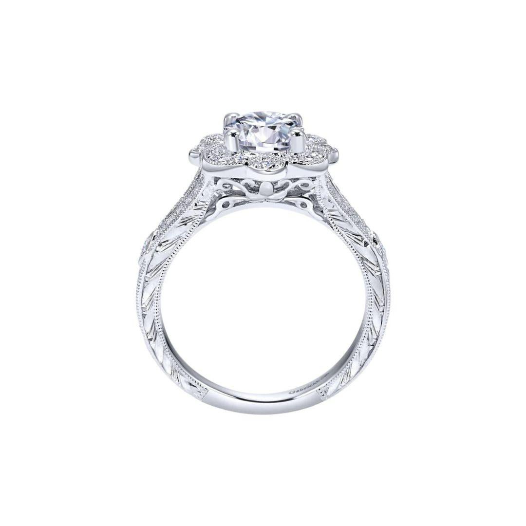 Ladies' Floral 14k White Gold Diamond Engagement Mounting. Split shank with delicate diamond pave and vintage inspired milgrain lead up to an intricate floral halo. Diamond etchings on the side of the ring. Center diamond is I color, SI2 clarity, 1