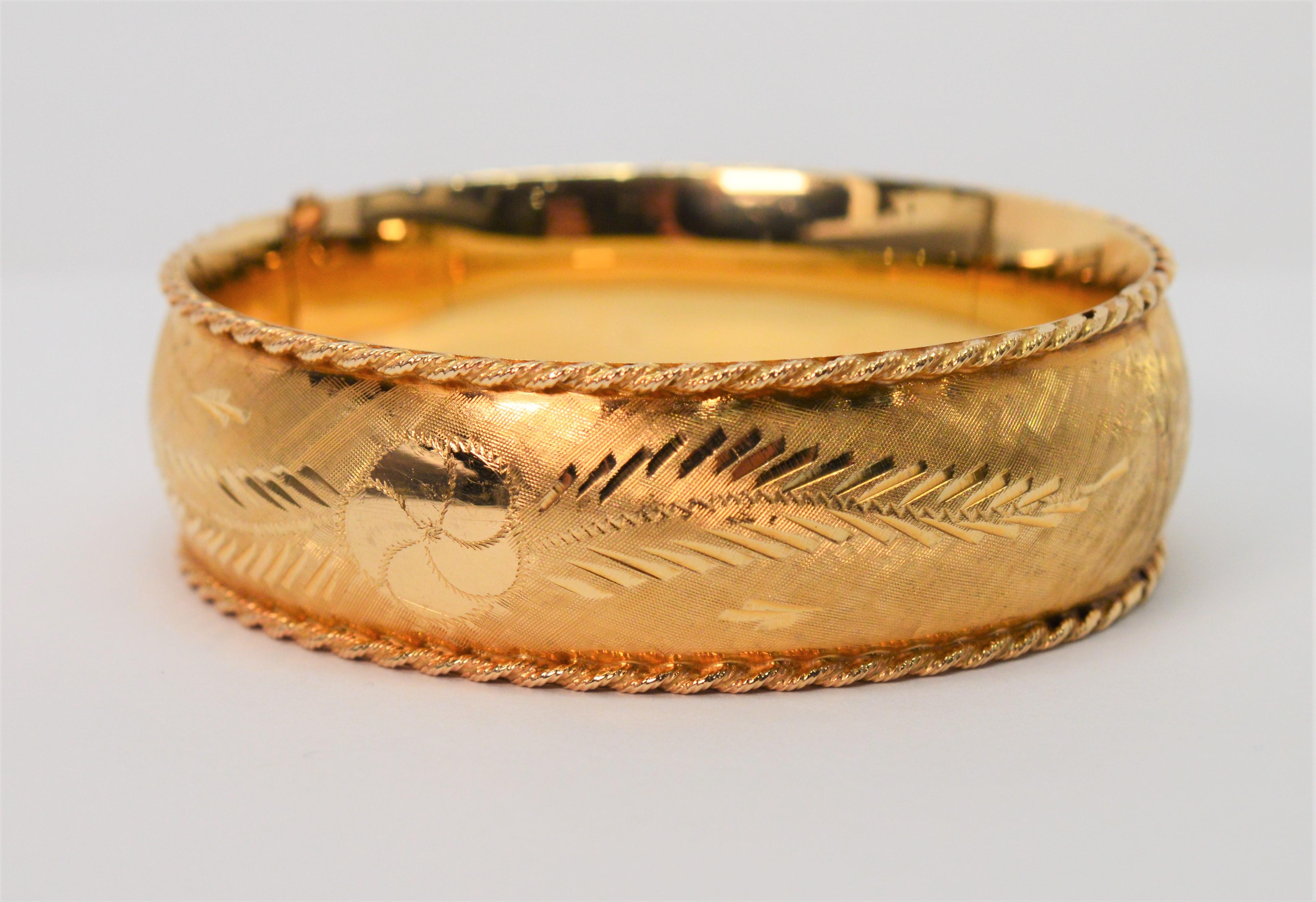 The defining beauty of complimenting satin and bright gold finishes along with an accomplished display of hand engraved textures makes this 14K fourteen karat yellow gold bangle remarkable.
Its floral leaf inspired design appears both front and