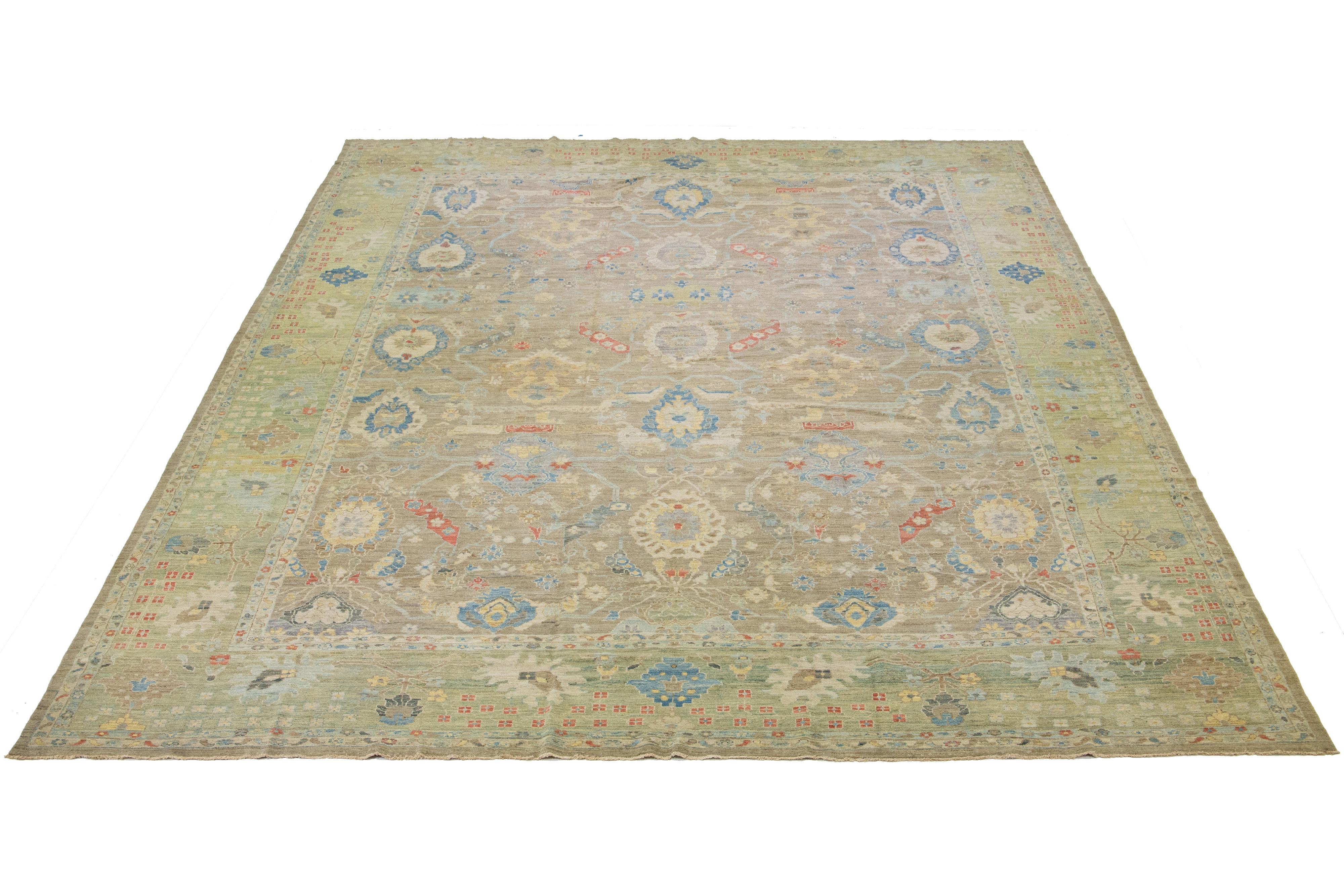 This oversized Sultanabad classic style has been meticulously transformed into a contemporary masterpiece. Crafted with great care, this magnificent wool rug has a light brown field with a green frame. Its all-over floral motif. To enhance its