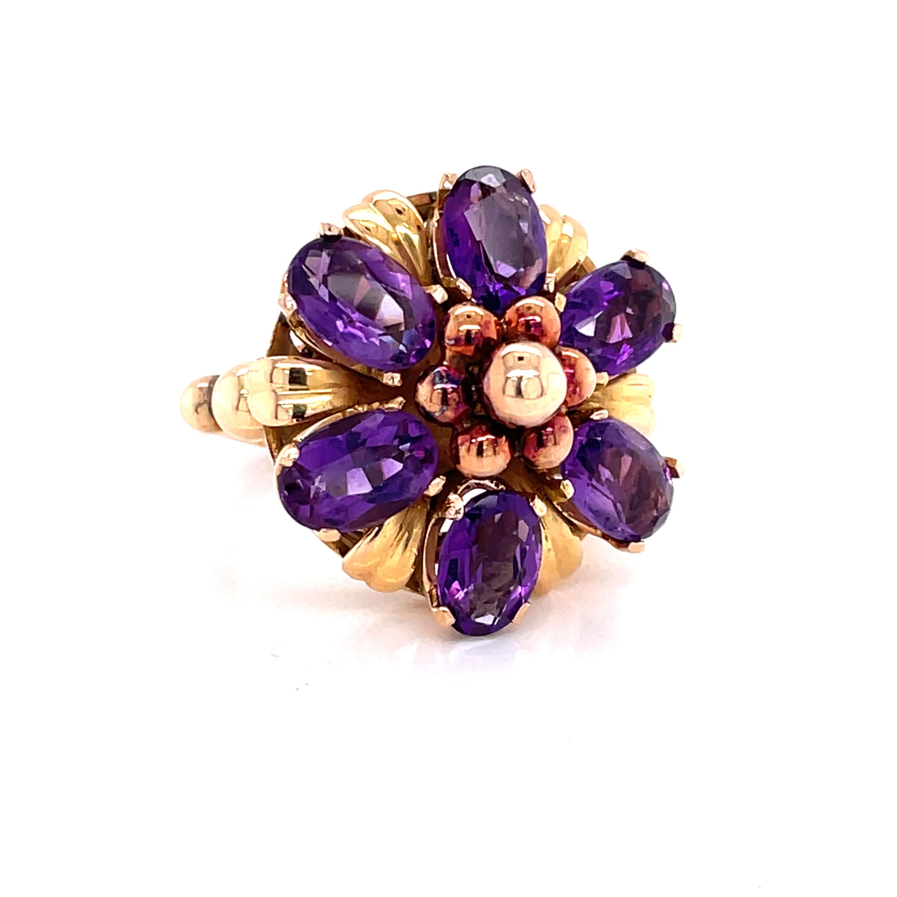 Six vivid .23 carat oval faceted amethyst gemstones, 1.38 carat total weight, are accented with petals of bright eighteen karat 18 karat yellow gold to create this European handmade floral inspired cocktail ring. Impressive ornate adornments and