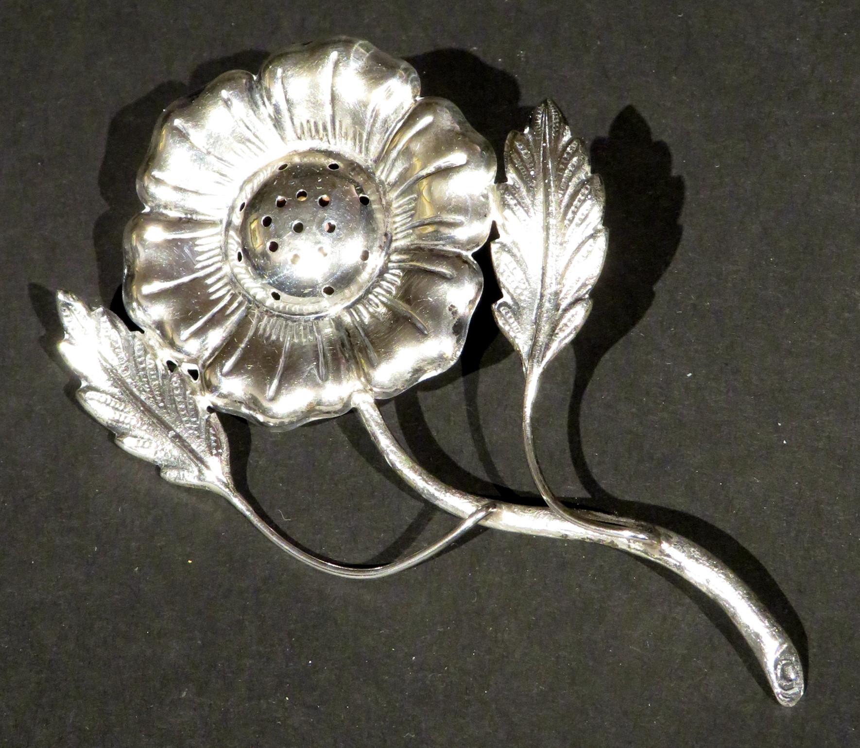 Cast in the form of a flowering vine, the embossed silver flower-head radiating out from a pierced centre, attached to a naturalistically inspired leafy stem. 
The reverse having a cork backed compartment to receive spice. 
No apparent marks, but