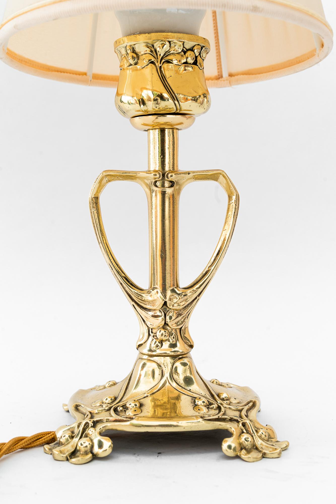 Lámpara de mesa Jugendstil floral con pantalla de tela viena hacia 1908
Latón pulido y esmaltado al horno
Se sustituye la pantalla de tela ( nueva )