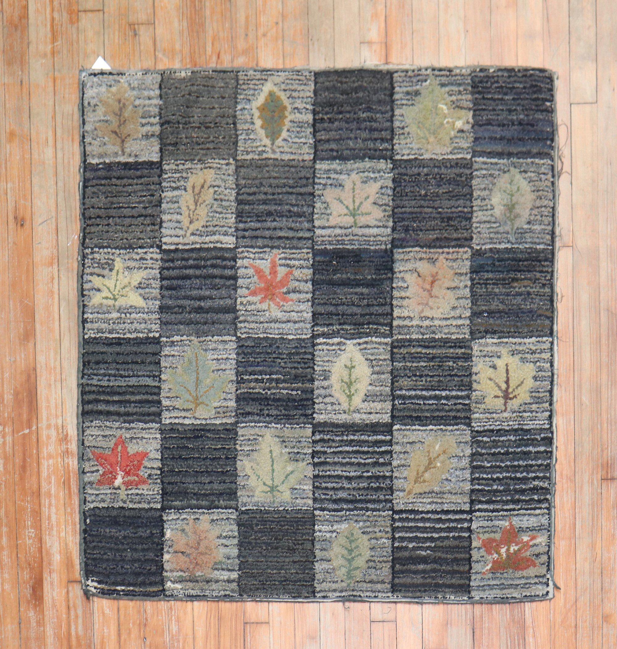 A handmade decorative American hooked rug from the middle of the 20th century with an assortment of leaves on a repetitive box pattern on a gray and charcoal ground

Measures: 3'6