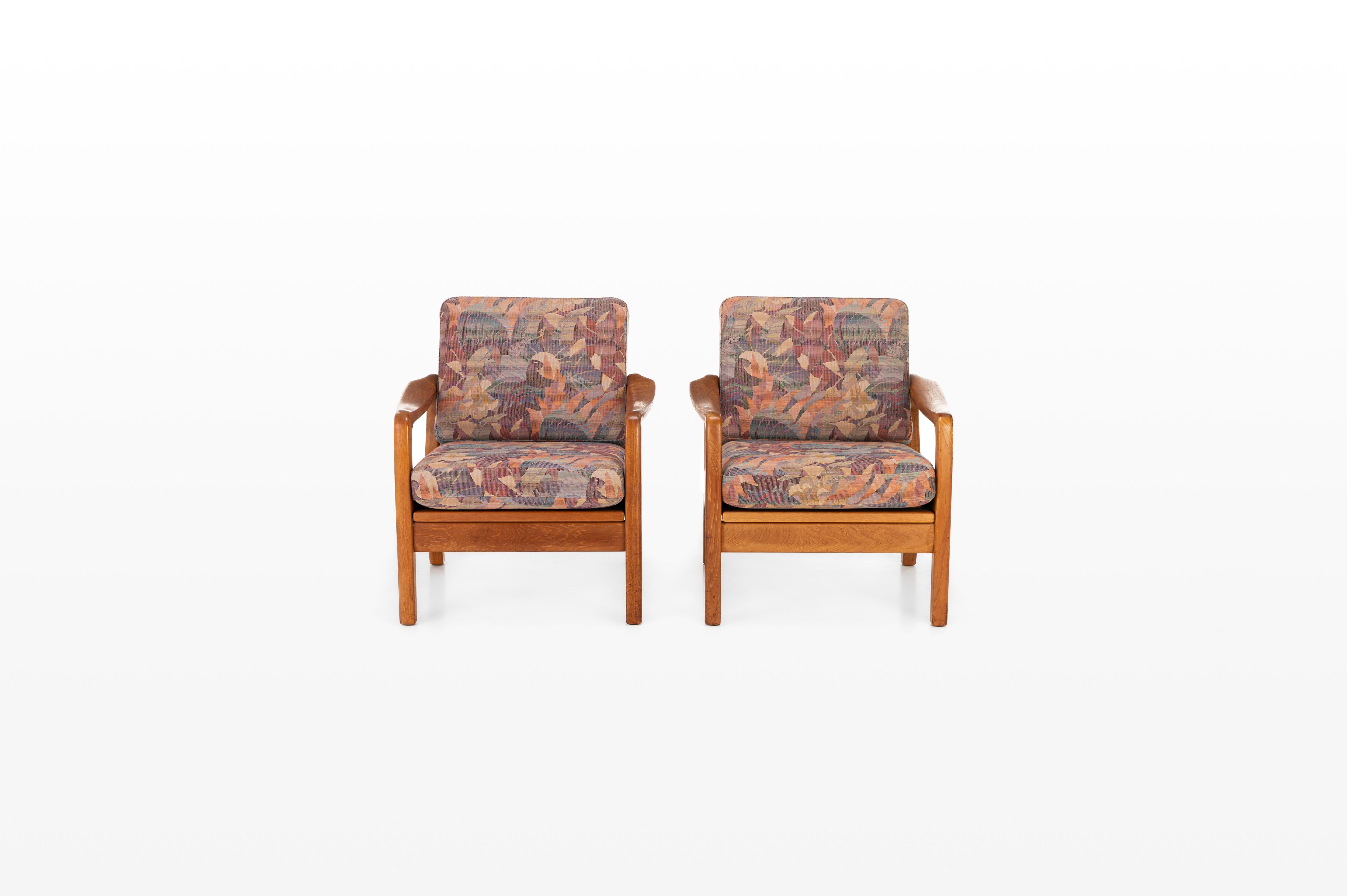 Set of two easy chairs designed by Juul Kristensen for JK Denmark. Produced in Denmark in the 1970s. The armchairs have a teak frame and the cushions still have the original tropical flower fabric. We also have the matching three-seater available.