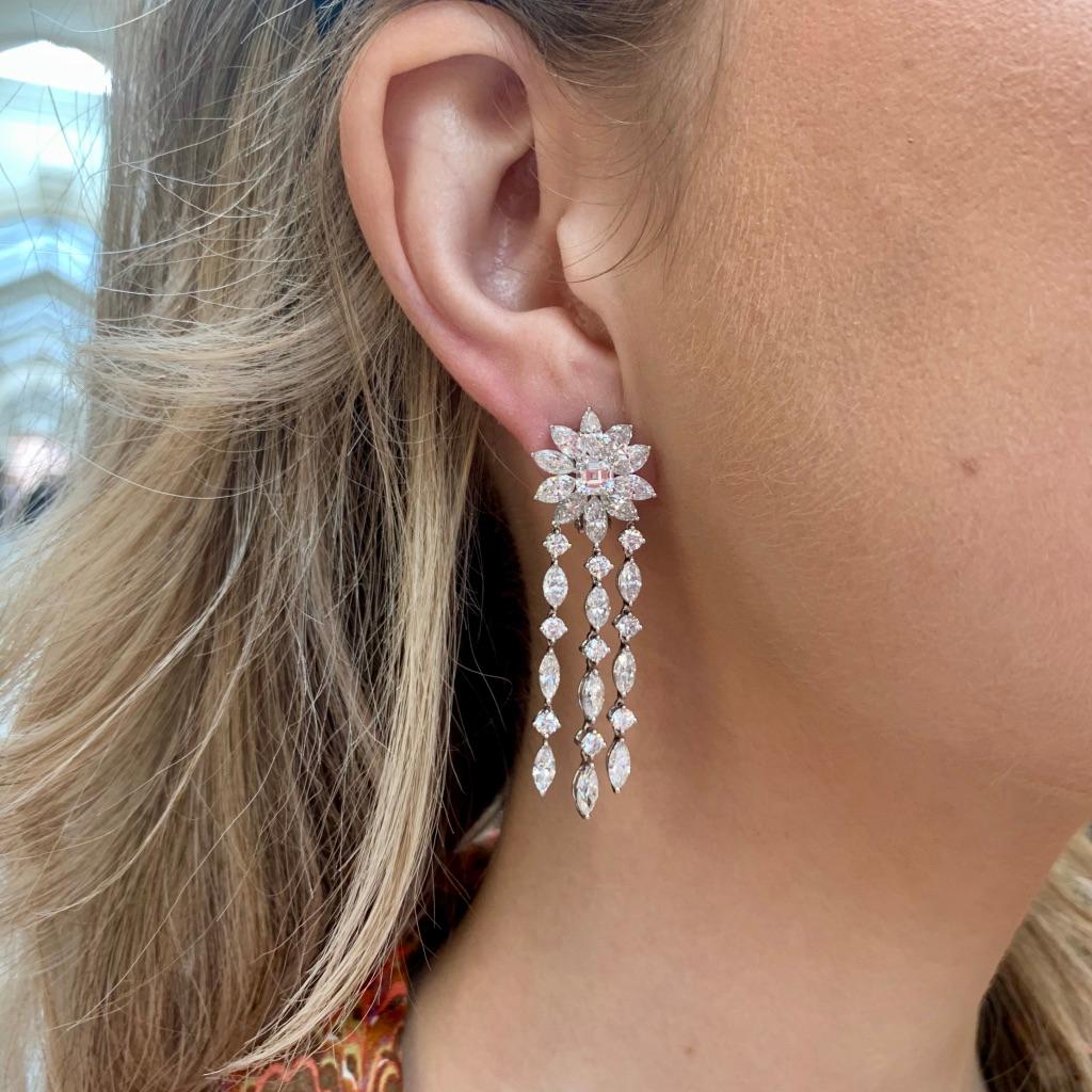 A beautiful pair of diamond cluster drop earrings set in platinum.

Each earring predominantly features a beautiful floral cluster set to the centre with a four-claw set asscher cut diamond. Dispersing from each asscher cut diamond is as spray of 10