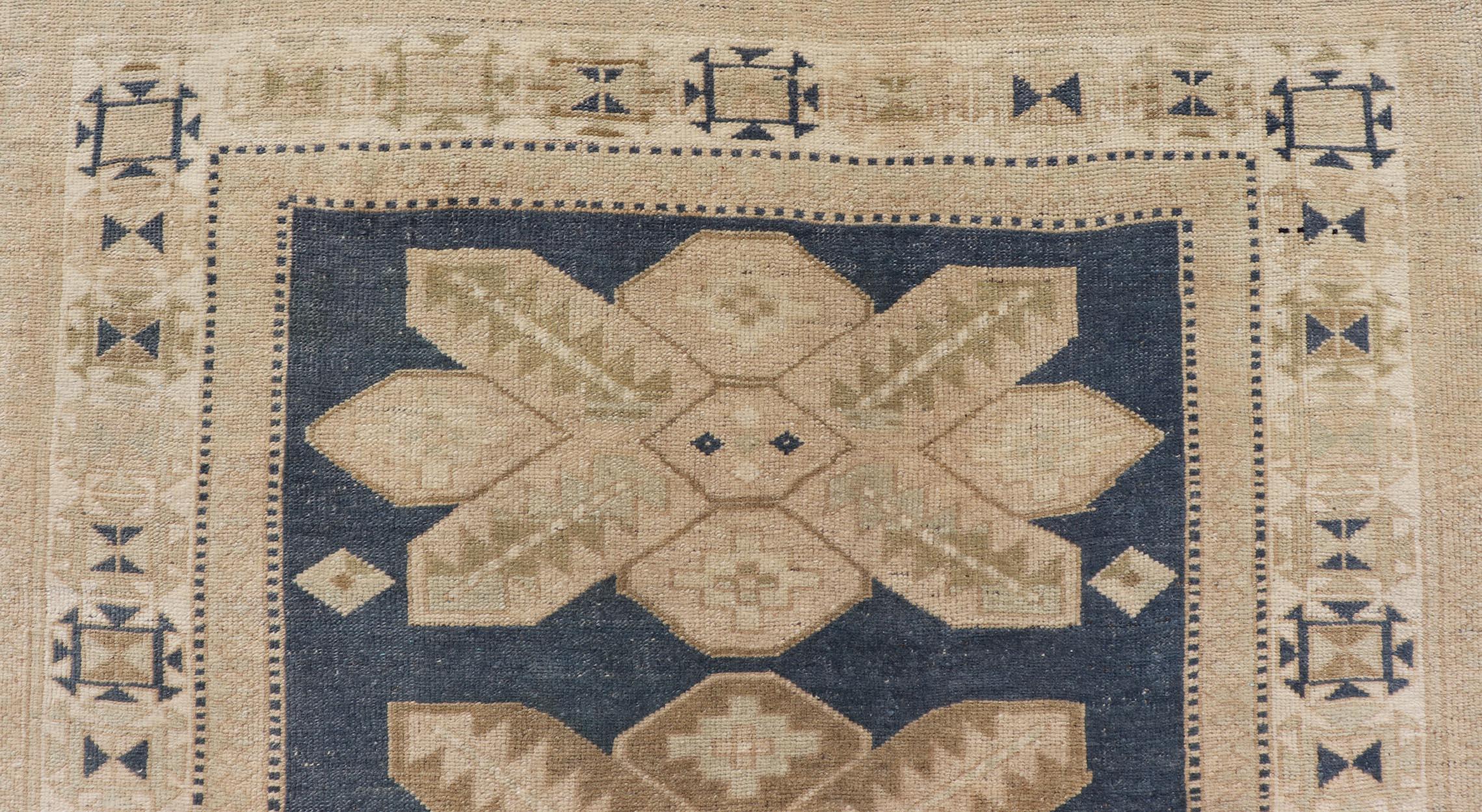Measures: 4'0 x 5'10.
This captivating vintage Turkish Oushak rug displays a bold geometric pattern in warm beige tones, set against a rich deep blue field. The central design features large, symmetrical medallions that draw the eye with their