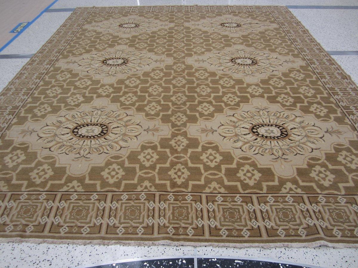 Floral medallions combine seamlessly with geometric patterns in a traditional rug of modern styling. Neutral tan and beige tones lend versatility without sacrificing style. Hand knotted wool.