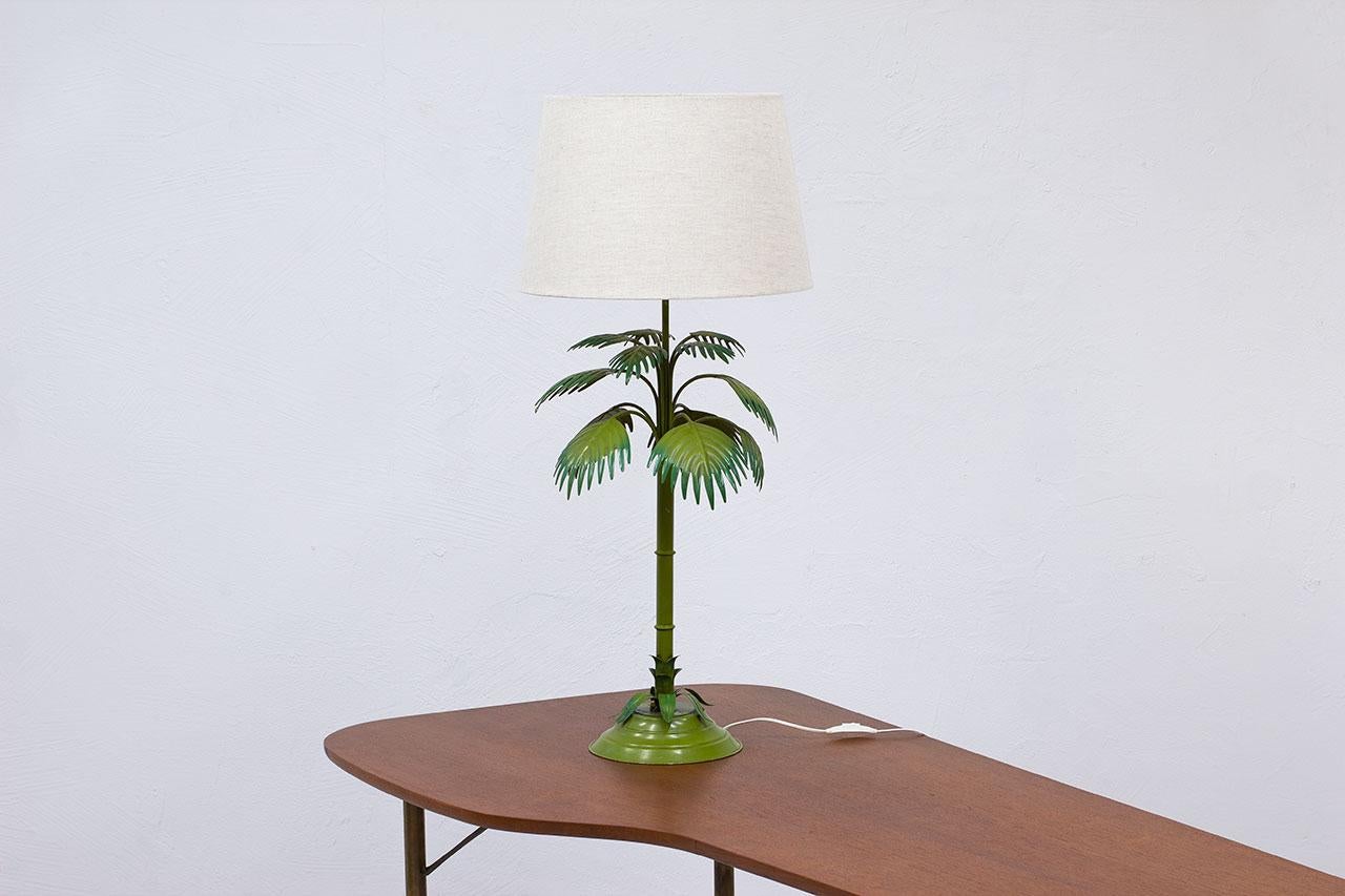 Elegant tall floral table lamp manufactured by Nordiska Kompaniet – NK in Sweden during the late 1960s. Model number 100-3. 
Made from enameled metal with a beige linen lampshade. Labeled underneath. Electricity with light switch on chord in working