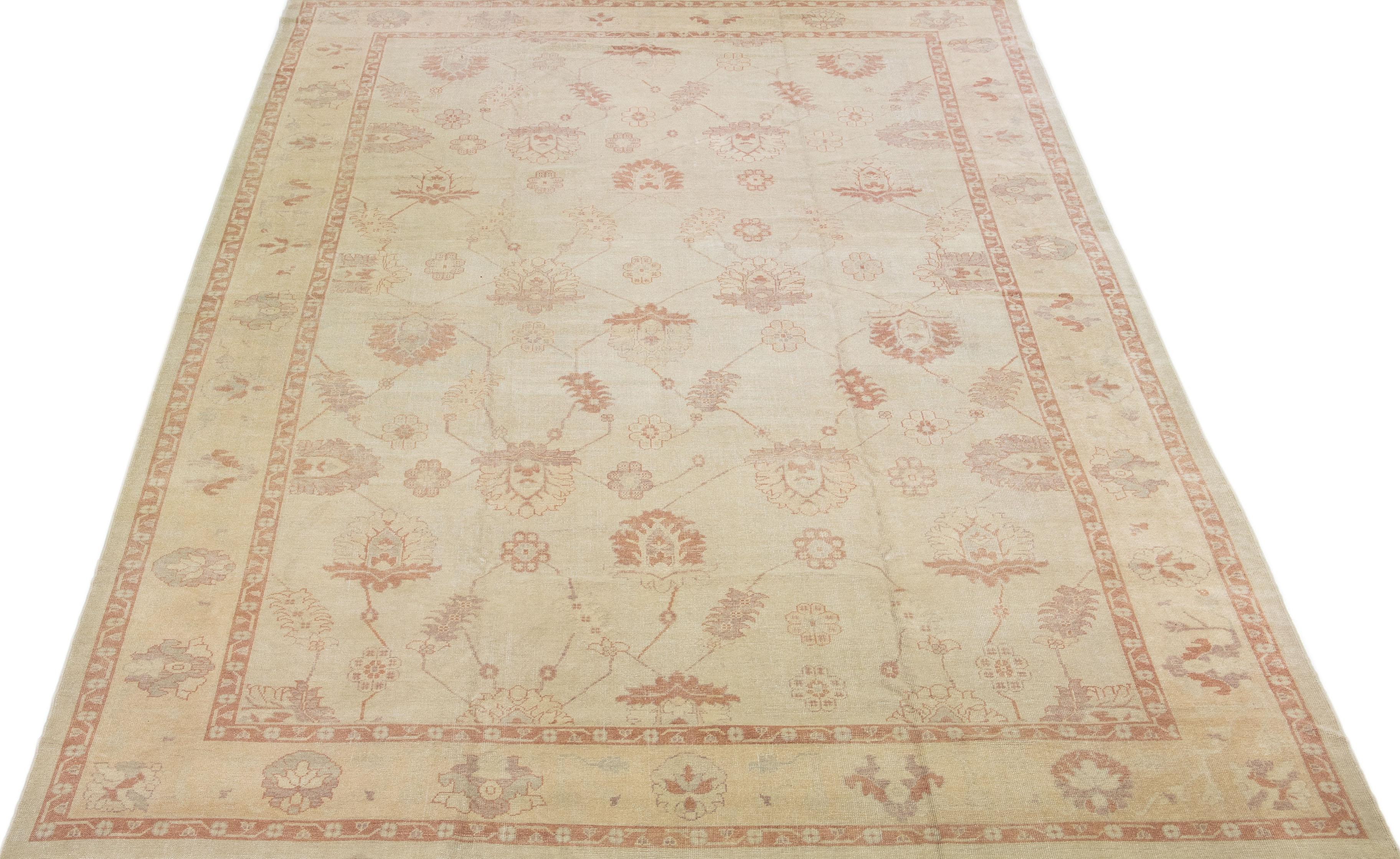 Beautiful modern Turkish hand-knotted wool rug with a beige color field. This rug has a designed frame with accent colors of orange-rust in a gorgeous all-over floral design.

This rug measures: 12' x 19'.